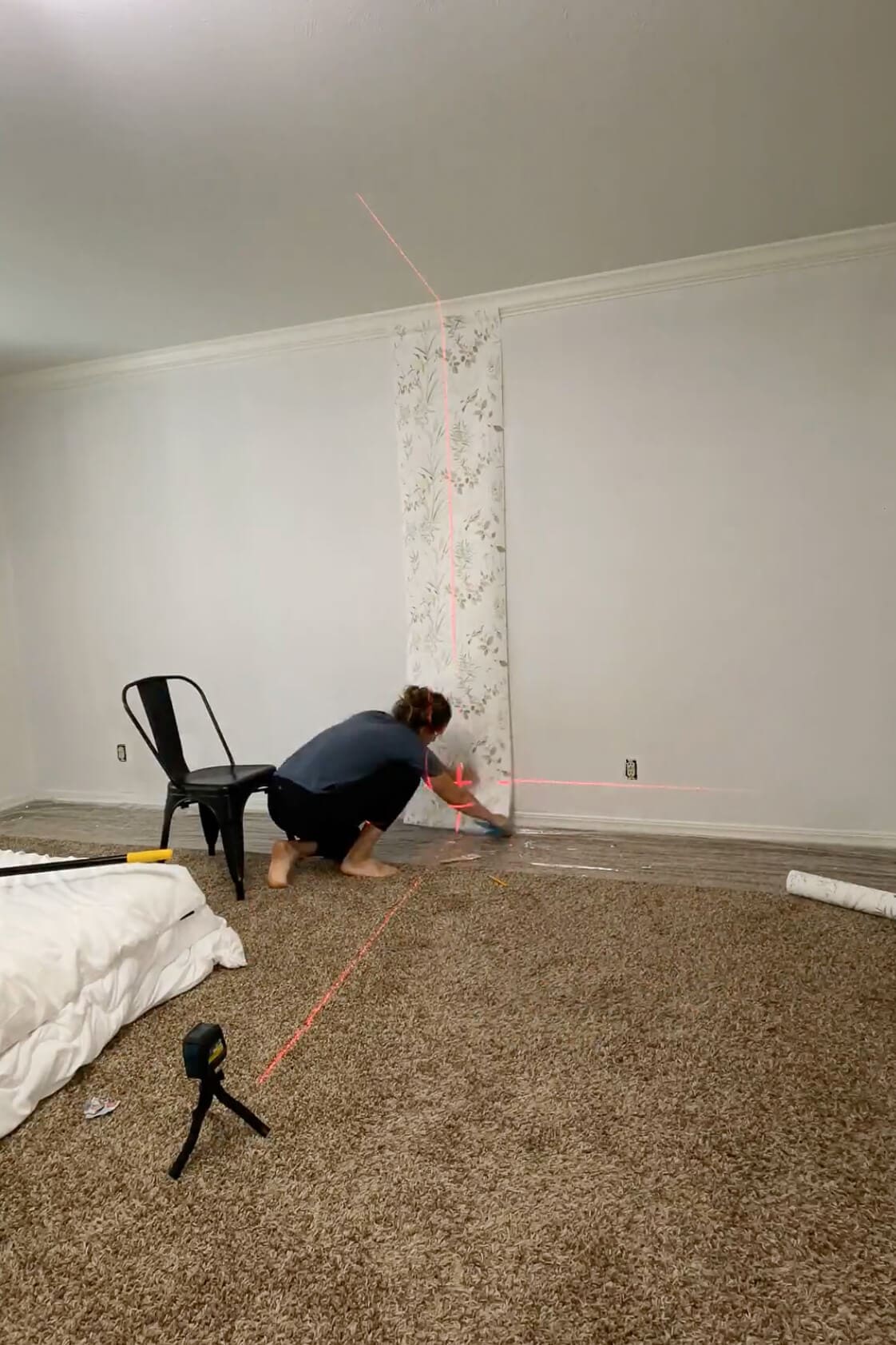 Applying the first panel of traditional wallpaper using a laser level for alignment