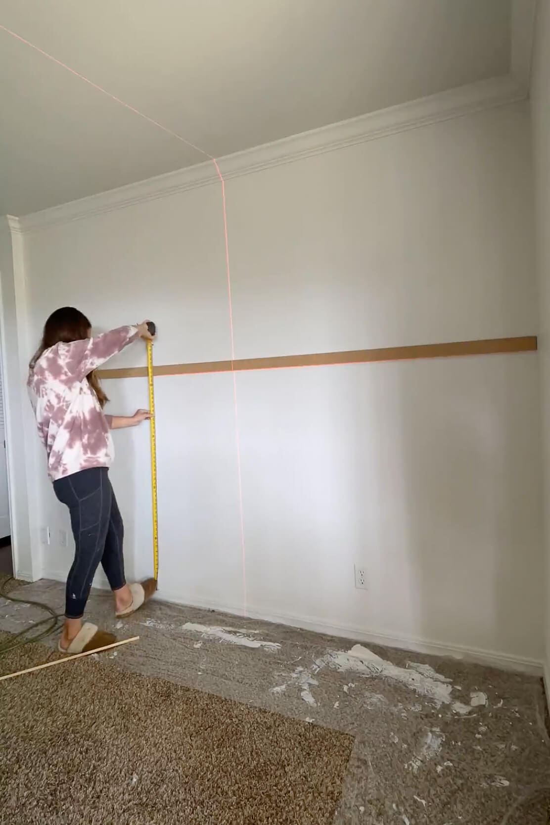 Using a tape measure to determine vertical spacing for trim while planning an easy DIY trim project.
