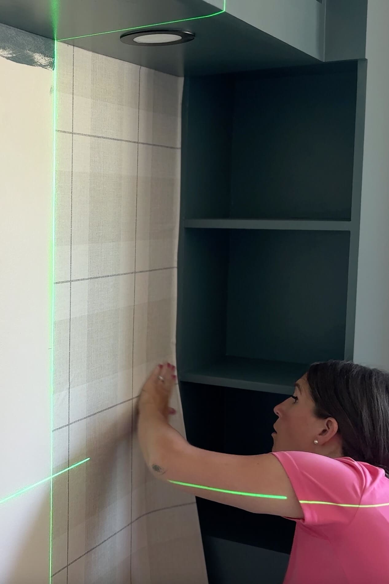 Pressing plaid peel and stick wallpaper firmly onto the wall with hands to secure it in place.