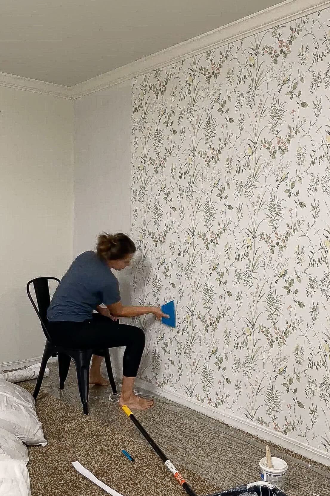 Smoothing down the edge of a traditional wallpaper panel near the corner of the wall