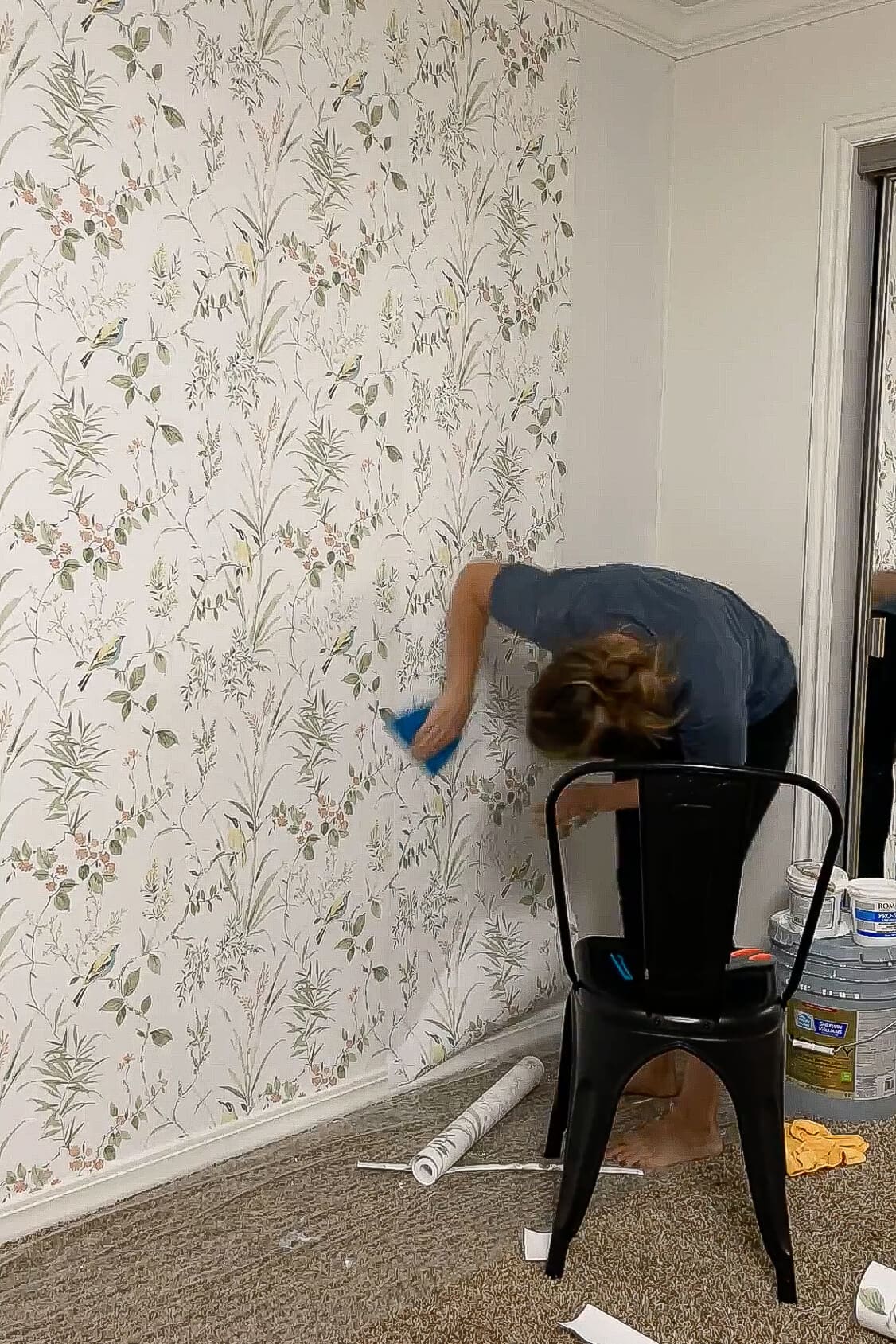 Using a smoothing tool to press traditional wallpaper flat against the wall