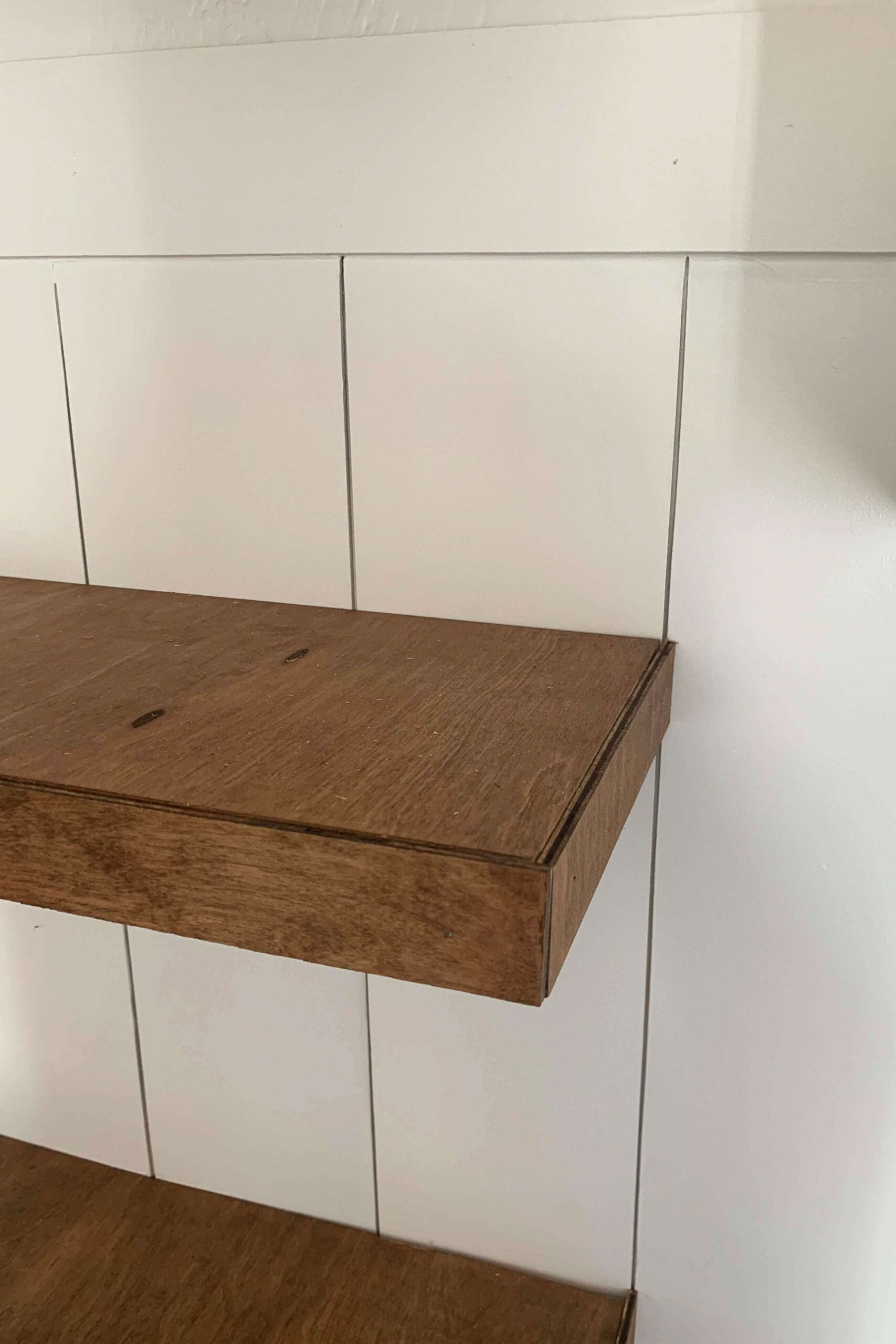 Close-up of a nearly completed DIY floating shelf made with stained plywood, installed over a white shiplap wall for a modern farmhouse kitchen upgrade.