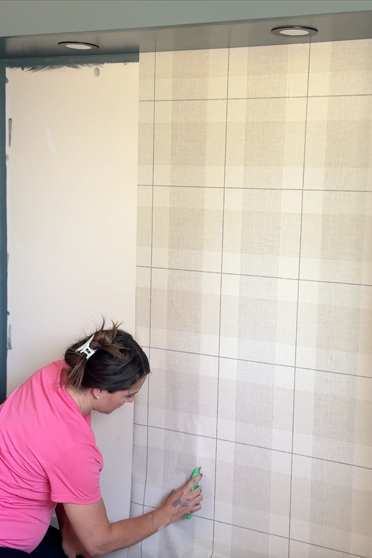 Smoothing wallpaper over an outlet cutout using a wallpaper tool during the final steps of installation.