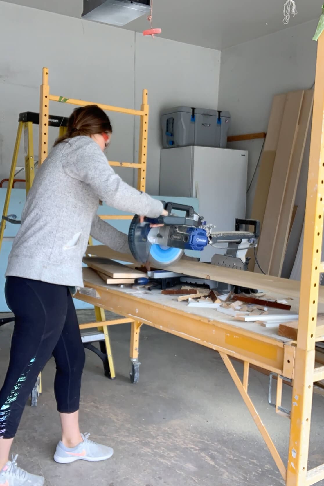 Cutting wood boards to length with a sliding miter saw inside a garage workspace during a DIY build.