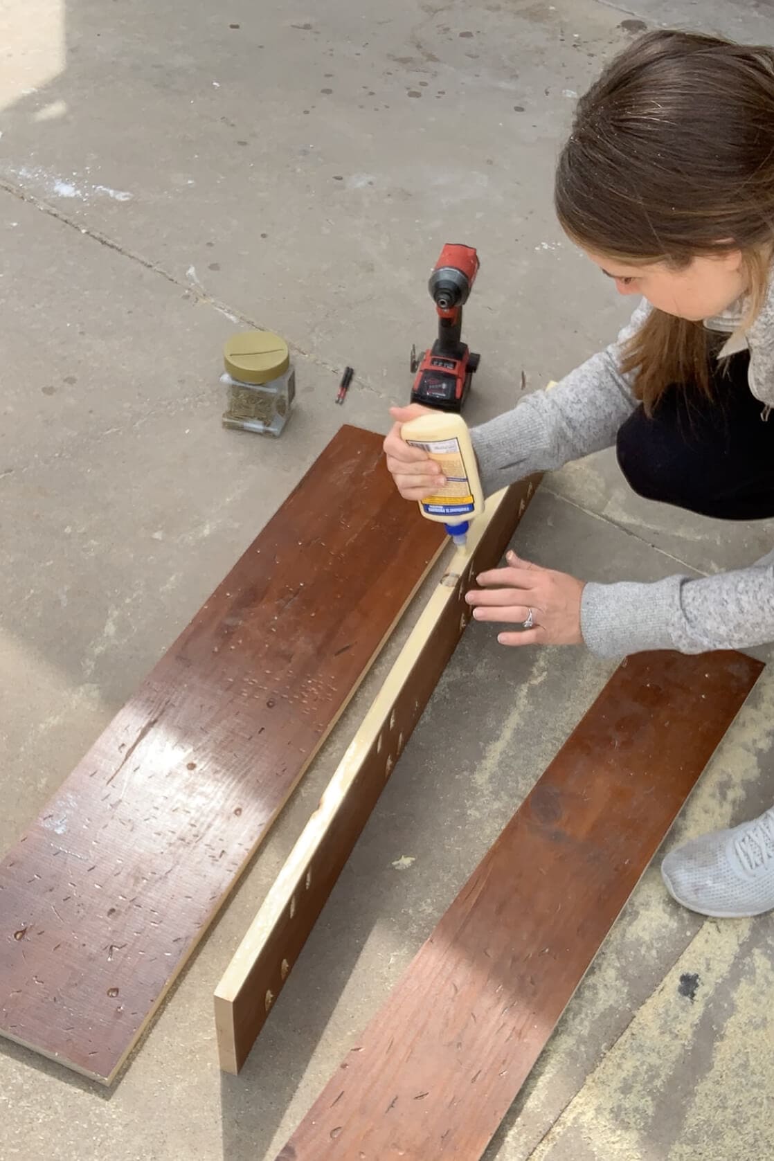Applying wood glue to repurposed mantel boards before clamping and joining them for a tabletop build.