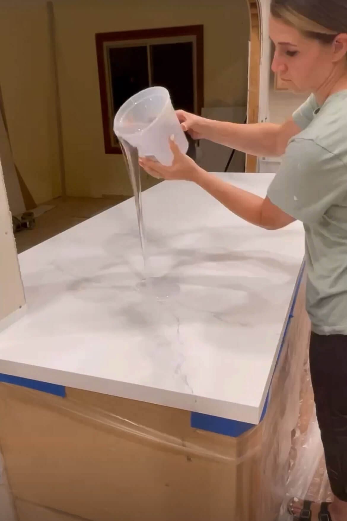 Pouring clear epoxy over a faux marble countertop during a DIY kitchen makeover