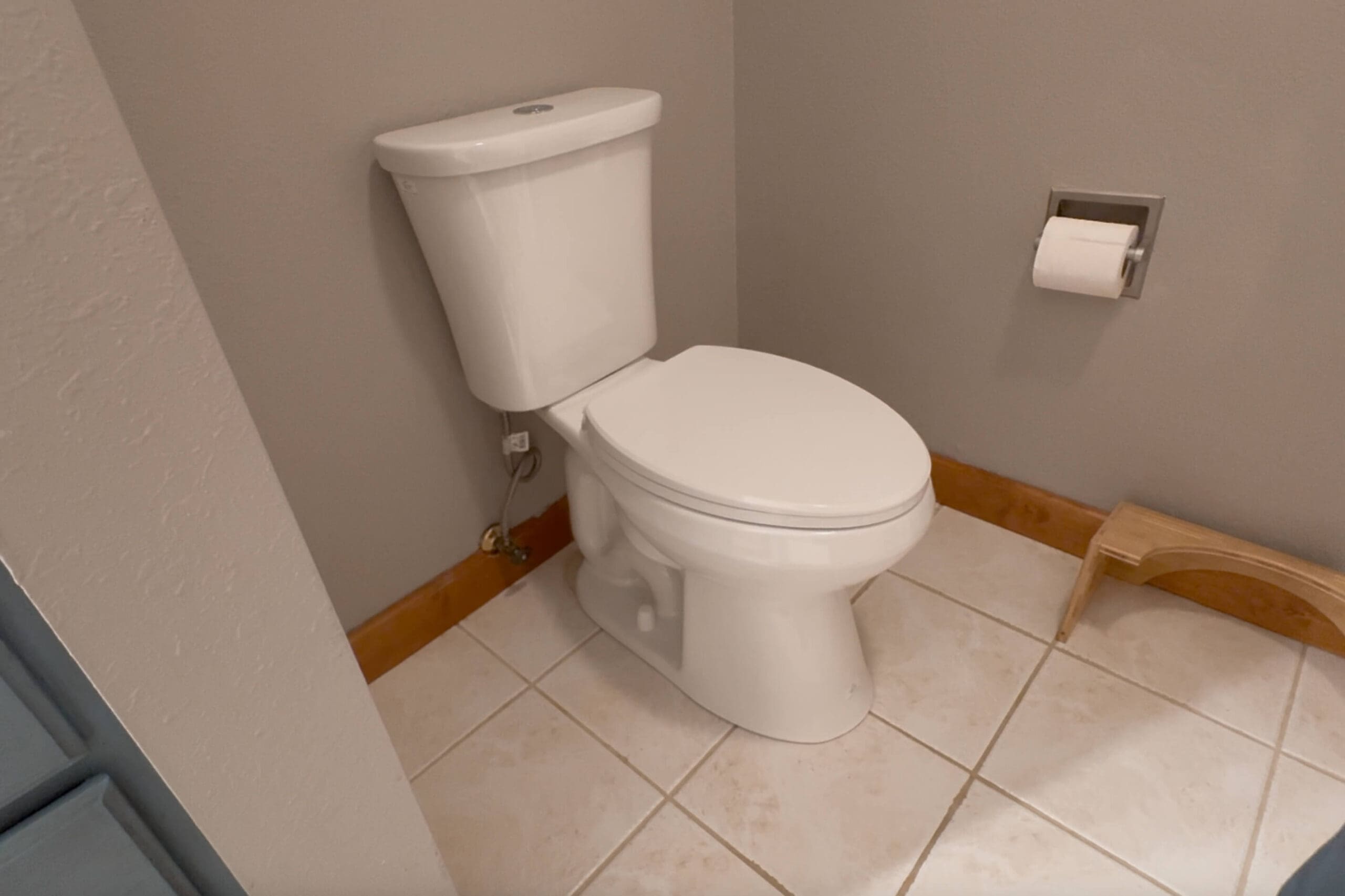 New toilet fully installed in the primary bathroom, shown with updated hardware and tile flooring after completing a DIY toilet replacement project.