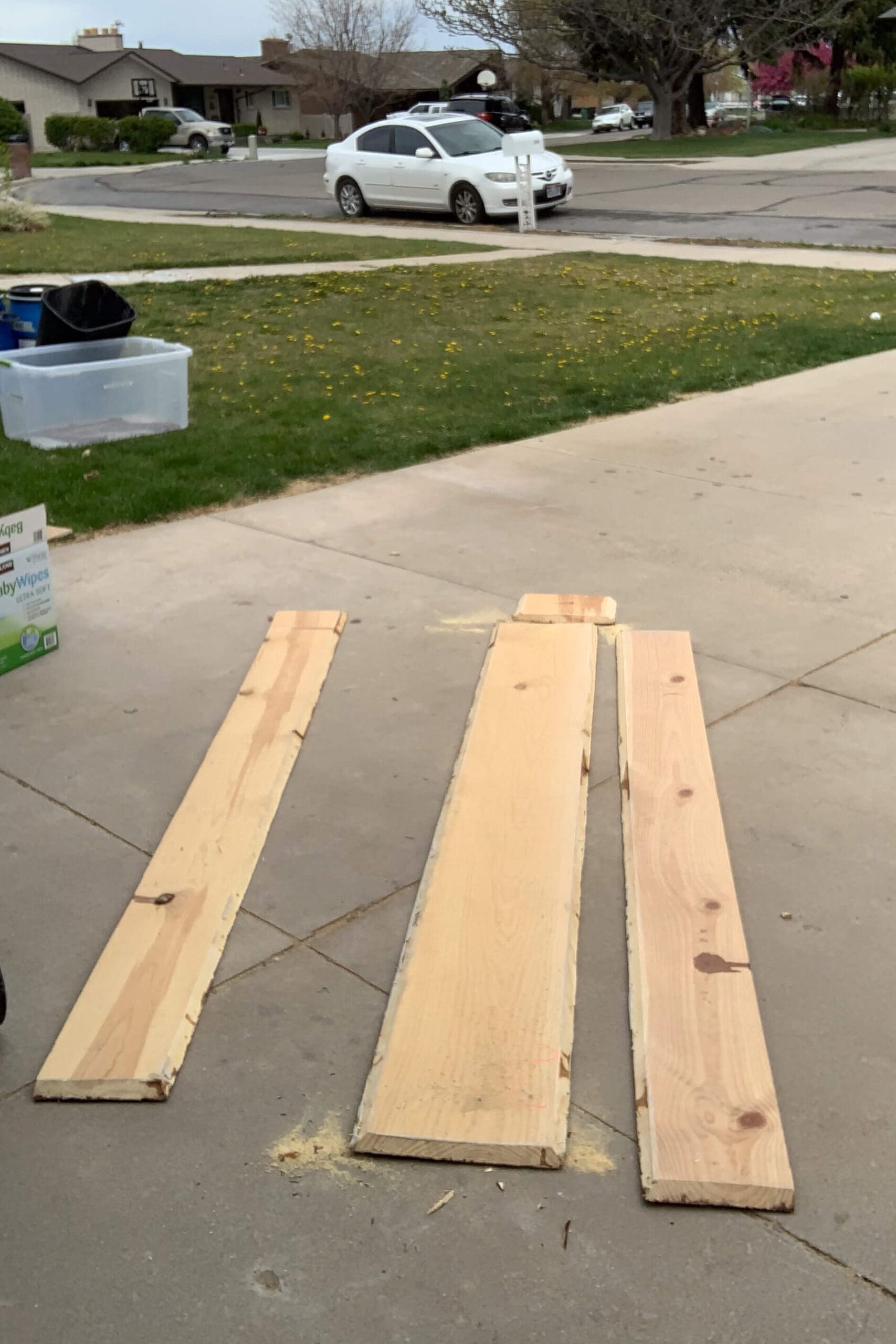 Disassembled pieces of a wood fireplace mantel laid out on a driveway, ready to be reused for a woodworking project.