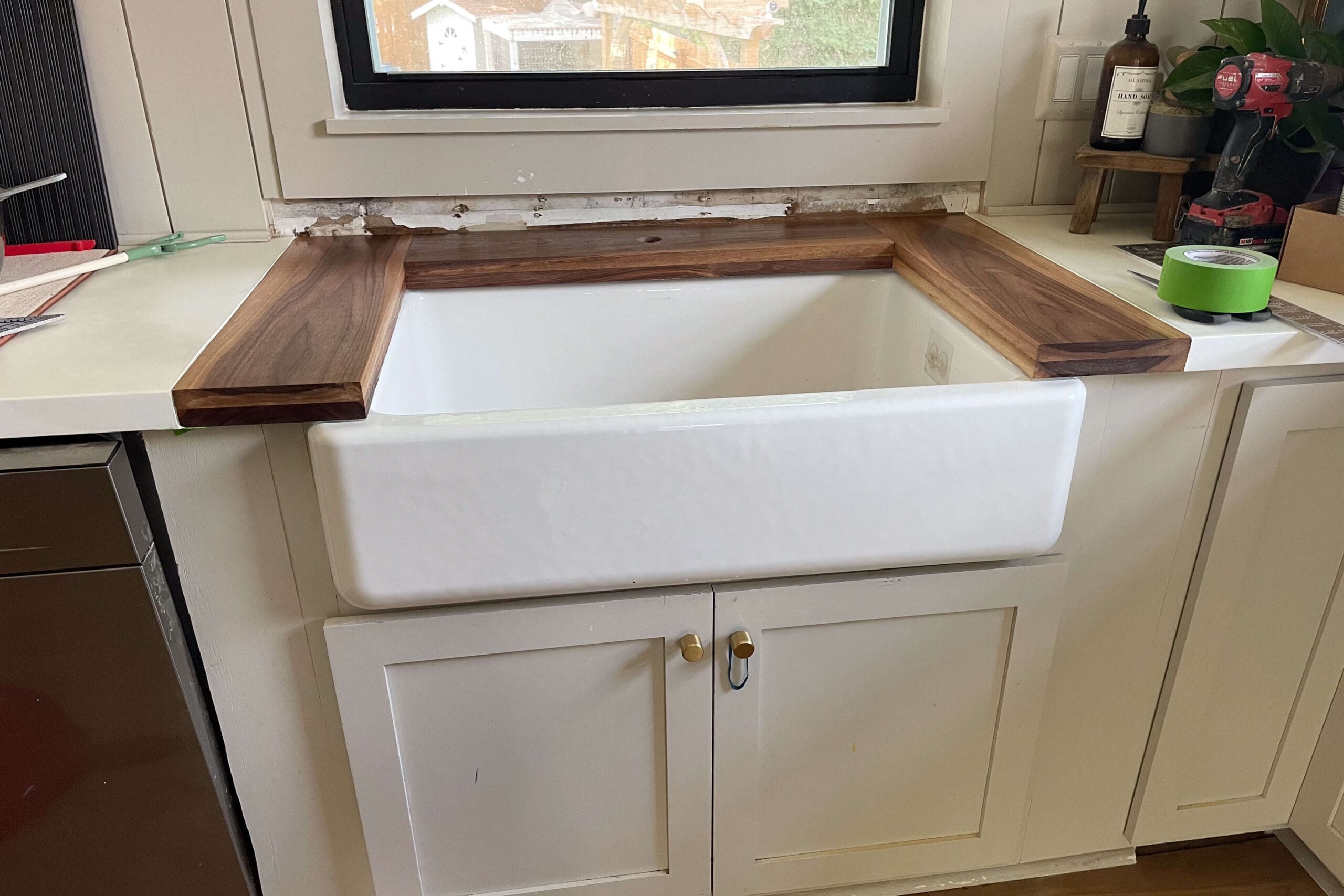 Installation progress of custom DIY wood counters around a farmhouse kitchen sink.