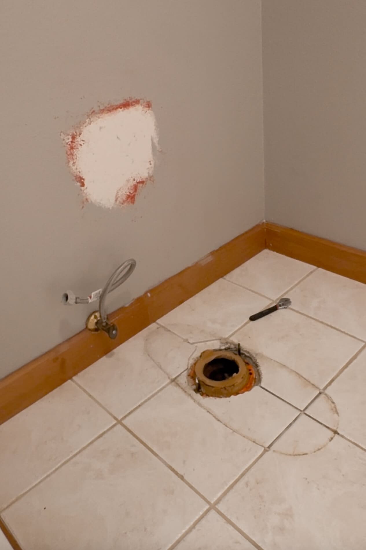 Bathroom floor with toilet removed, showing exposed toilet flange and old wax ring during the process of showing how to install a toilet.
