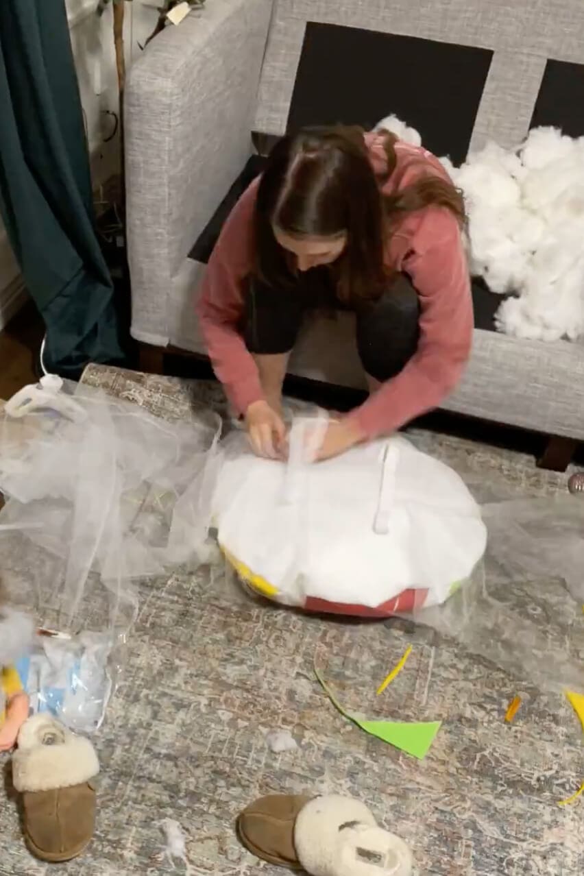Attaching white tulle around the base of a large DIY lollipop candy costume for kids.
