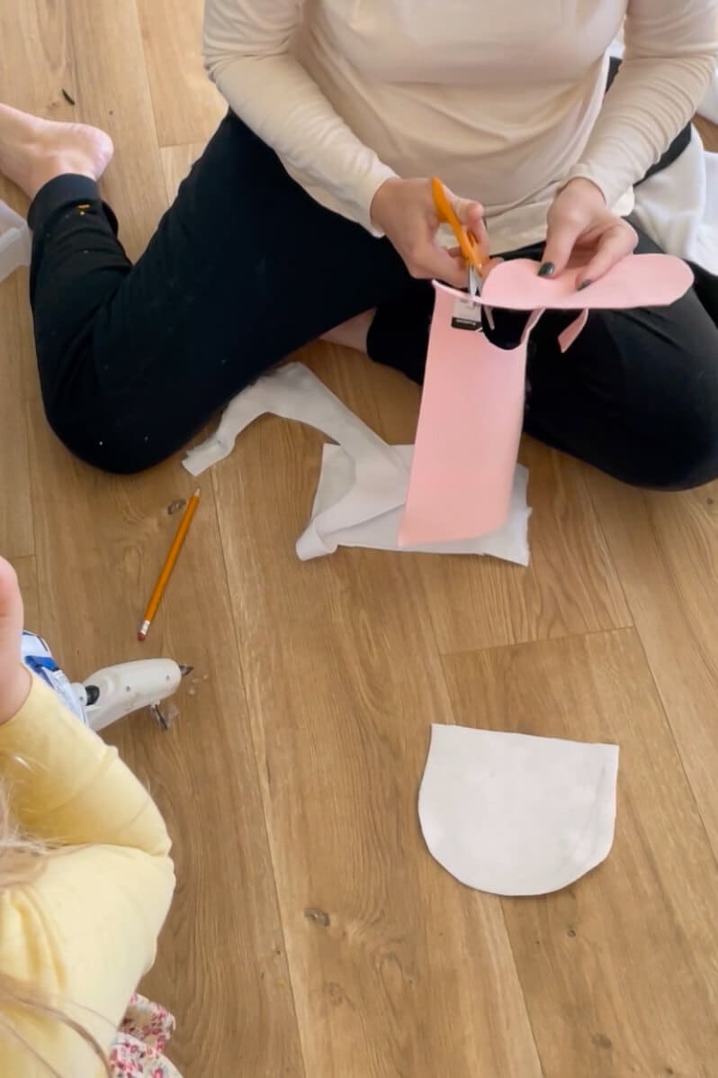 Cutting nostril openings into pink felt for the muzzle of a DIY cow costume mask.