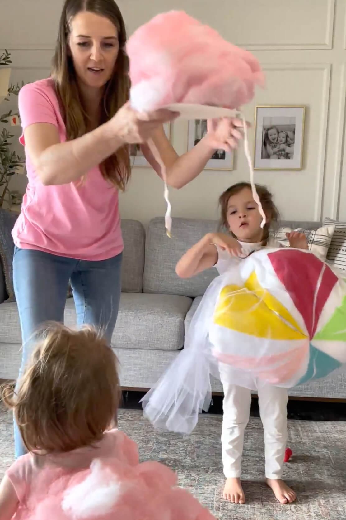 Mom holding a pink fluffy headpiece while kids wear colorful dress up outfits.