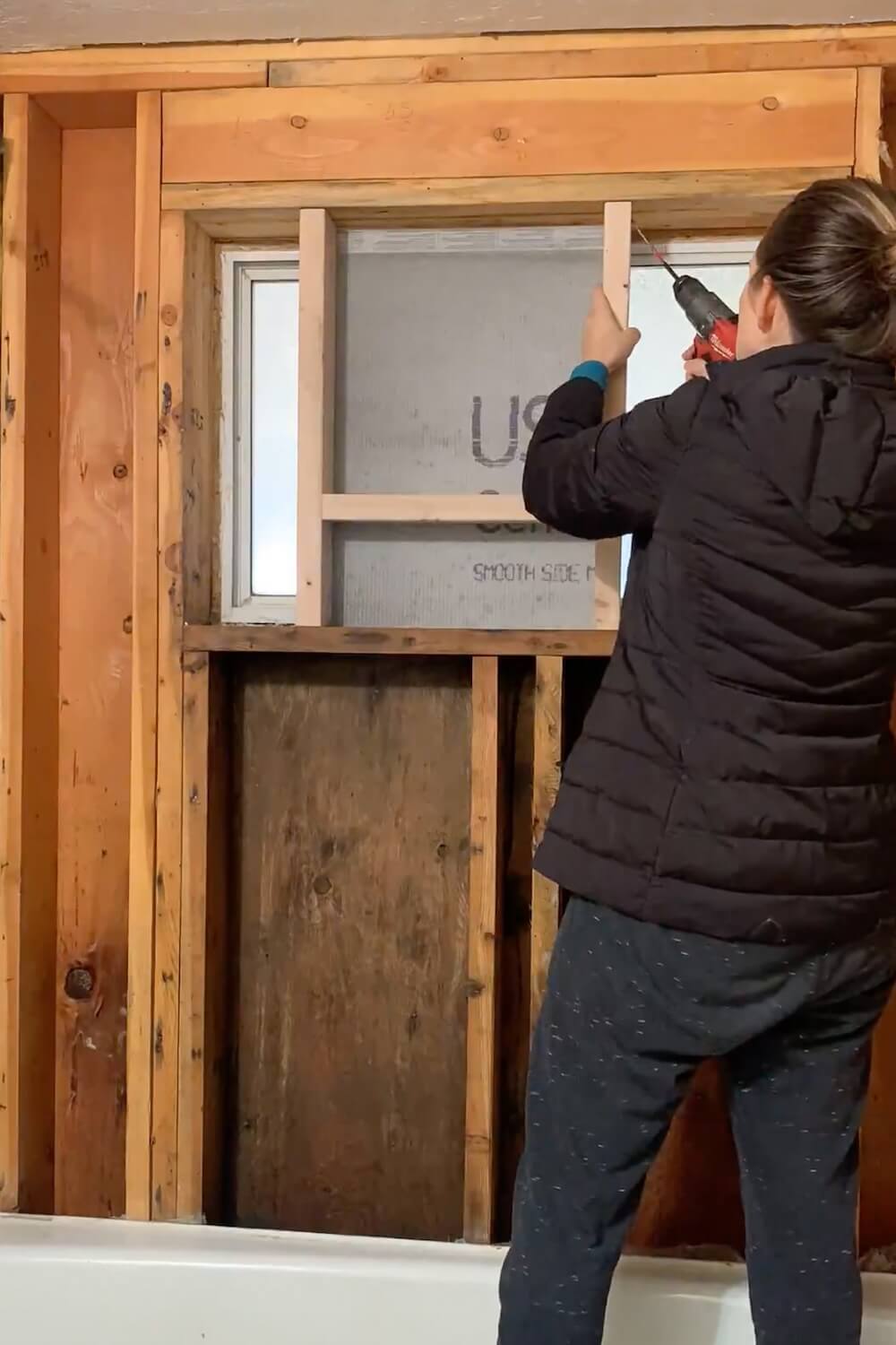 Fastening the left side of the shower niche frame to the wall stud during installation.
