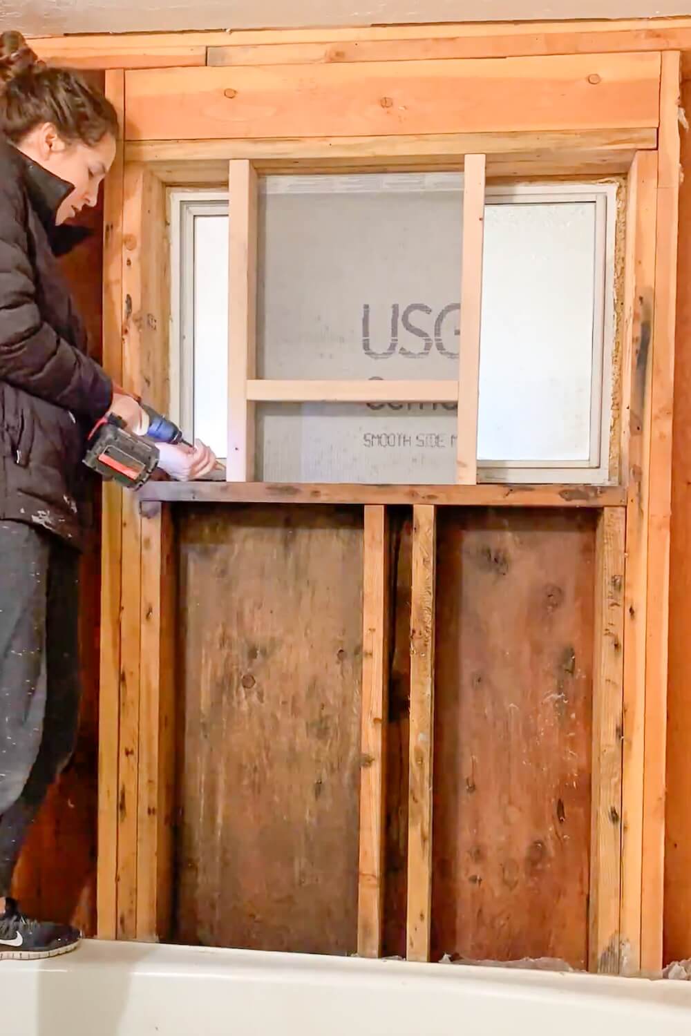 Securing the shower niche frame by screwing it into the right wall stud during installation.