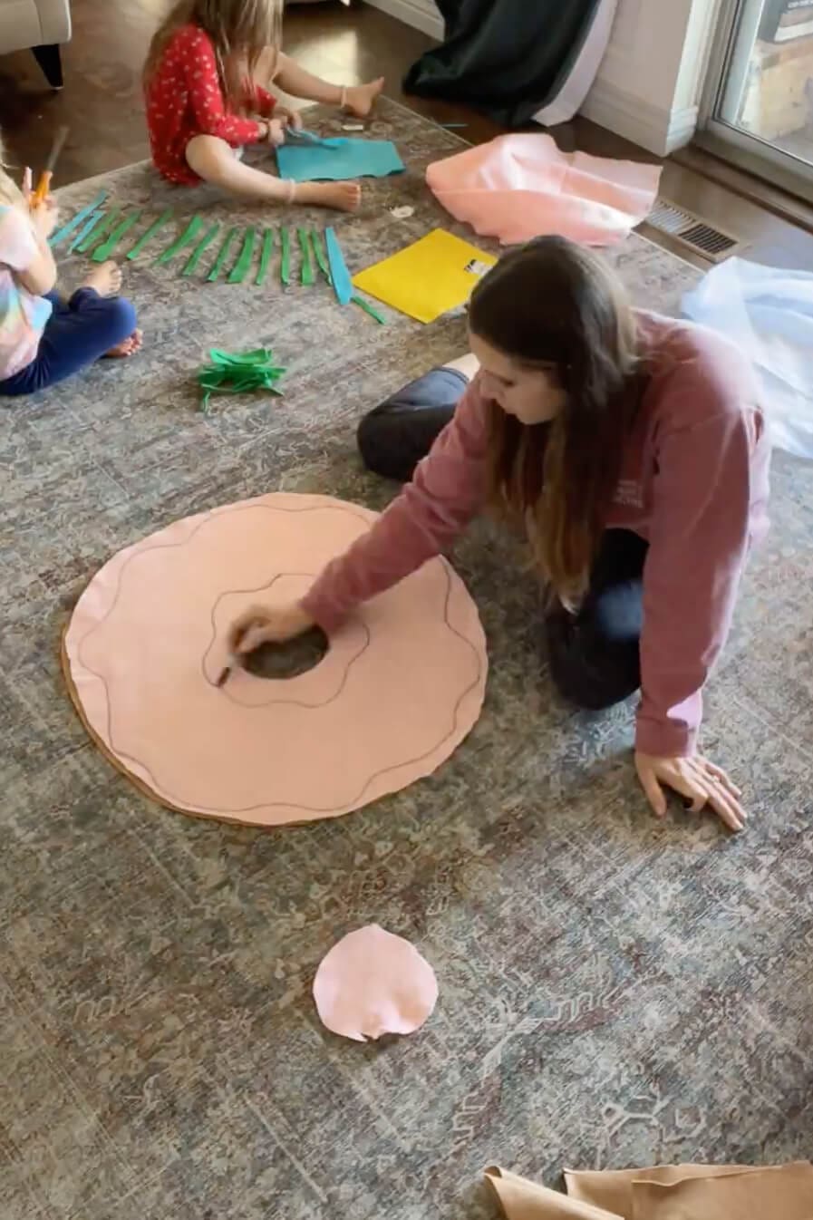 Drawing a wavy frosting outline on pink fabric for a handmade donut pillow.