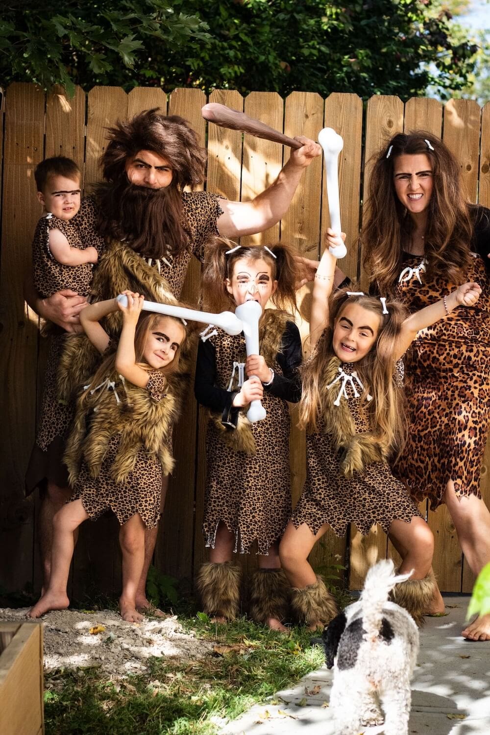 Family in DIY caveman costumes with faux fur and toy clubs.