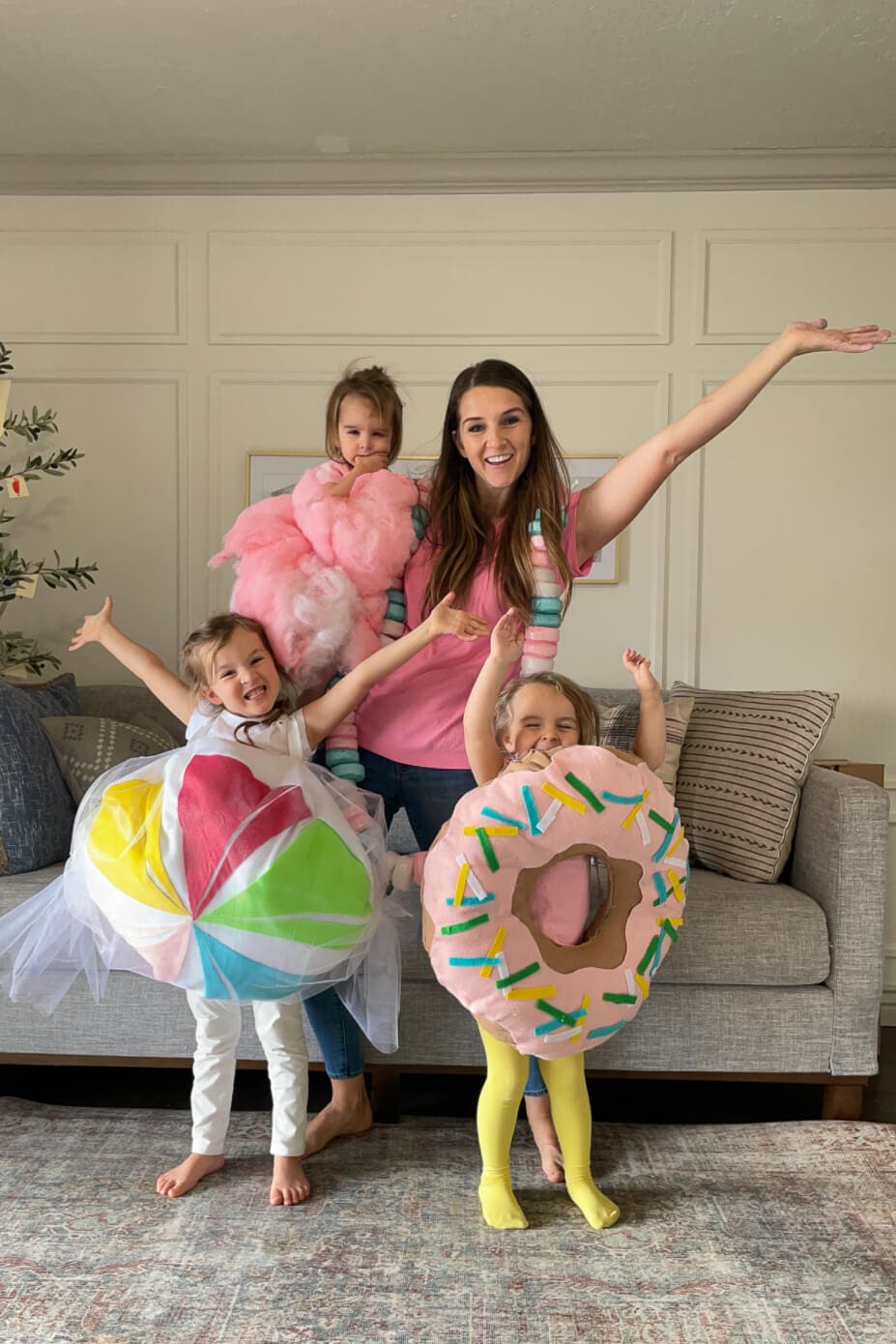Family costume ideas with a sweet treats theme, featuring cotton candy, candy necklace, lollipop, and pink frosted donut costumes.
