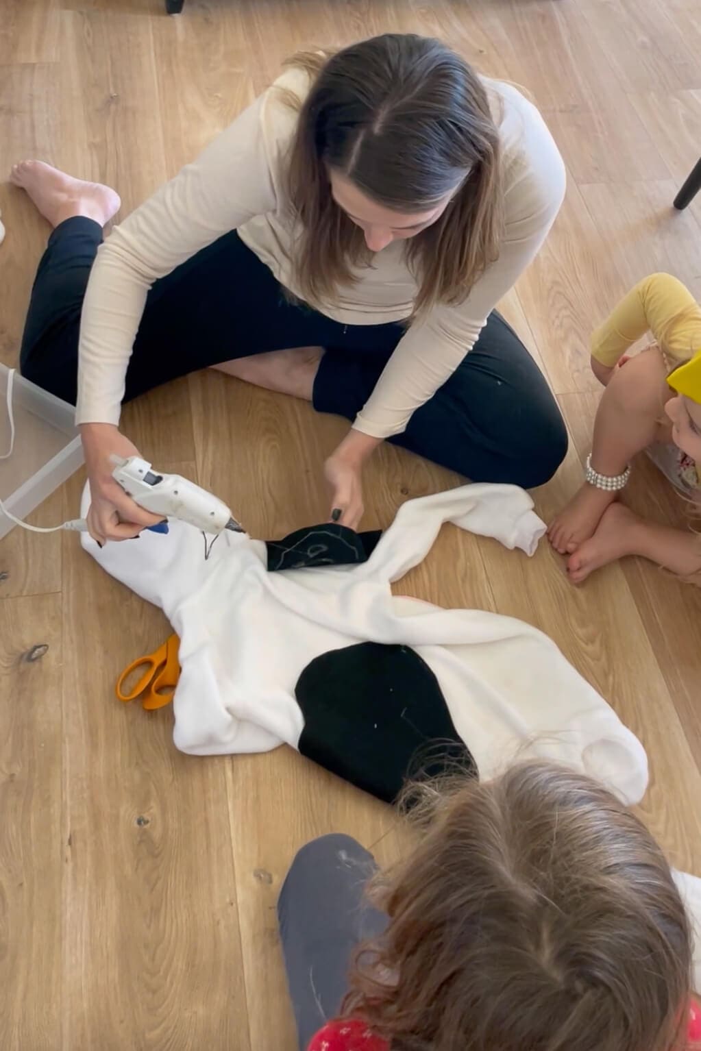 Gluing black felt spots onto a white jumpsuit to create a no-sew, homemade Halloween costume.