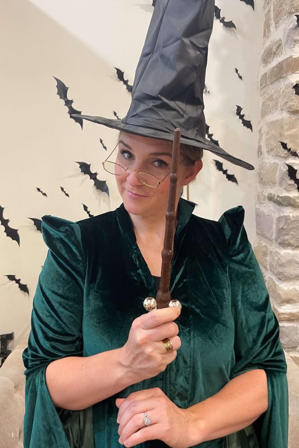 Woman in Harry Potter Halloween costume as Professor McGonagall holding a wand and wearing glasses with witch hat.