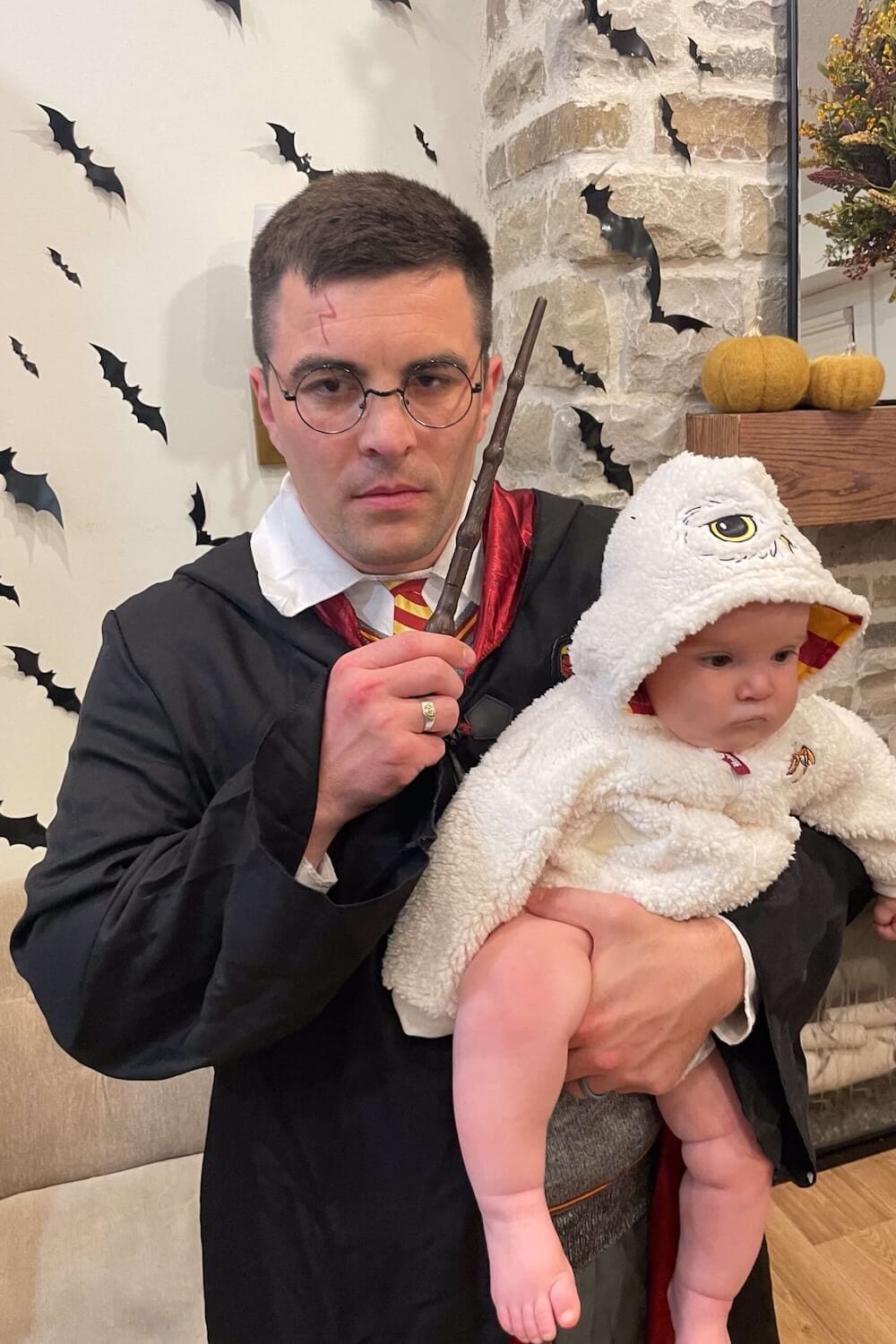 Dad dressed as Harry Potter holding baby in Hedwig owl costume for family Halloween.