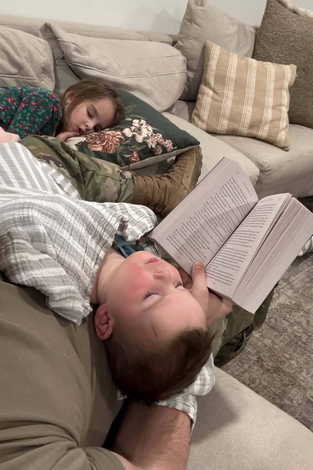 Dad reading a Harry Potter book out loud while kids fall asleep on the couch, cozy family reading time.