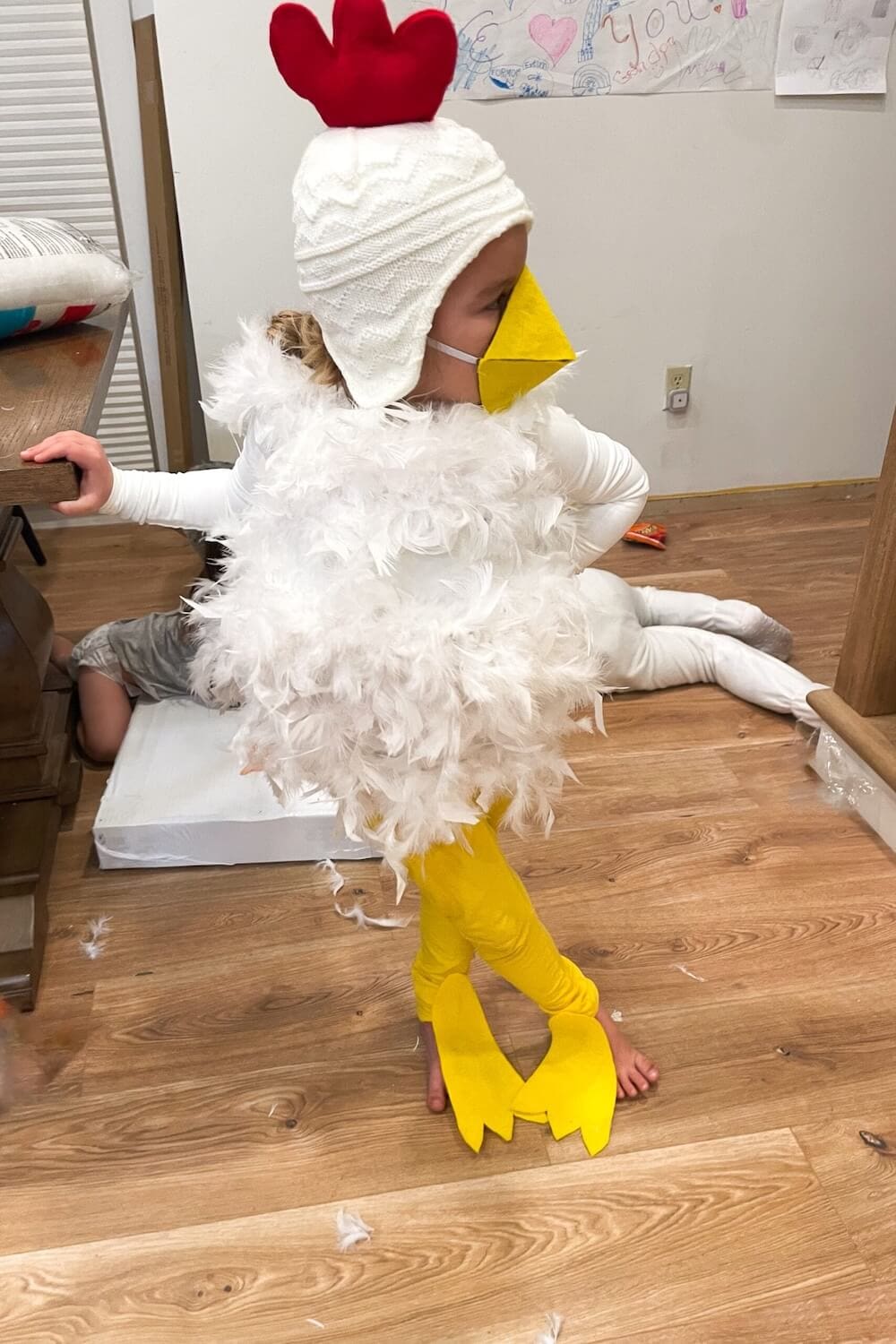 Side view of finished DIY chicken costume with feathered body and felt beak.