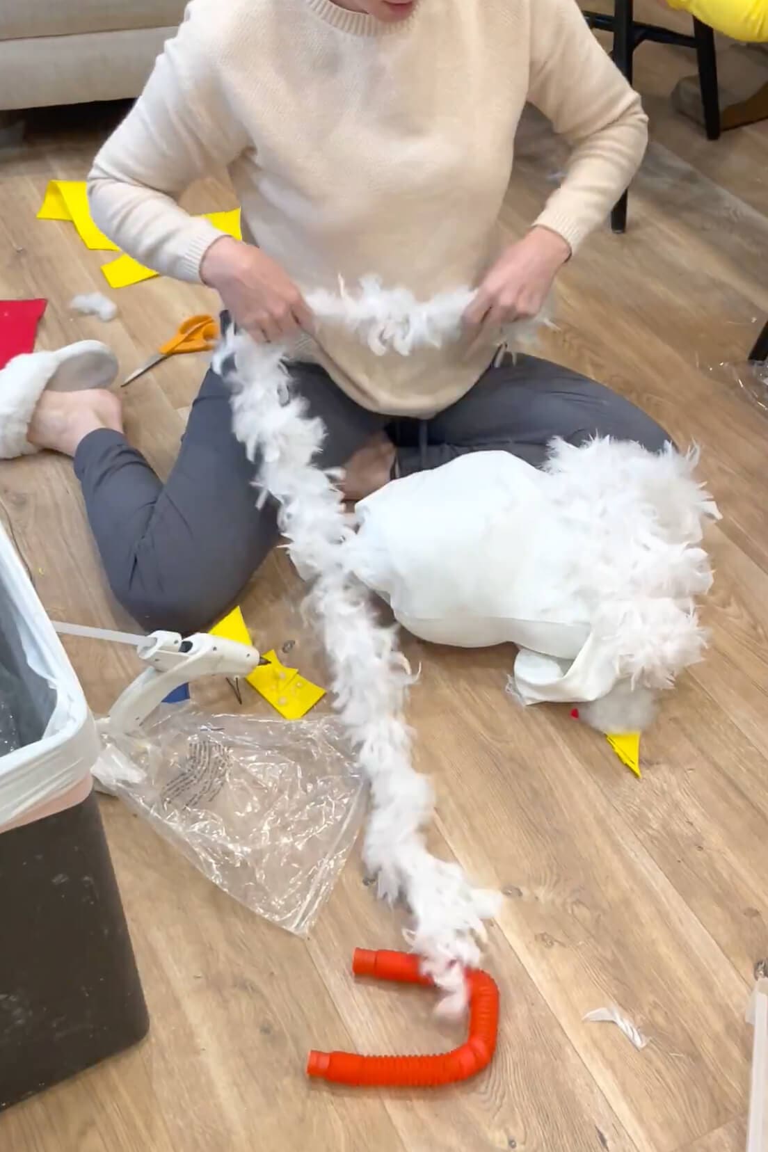Making a DIY chicken costume by attaching white feather boas to a hoodie with hot glue for an easy no-sew Halloween costume project.