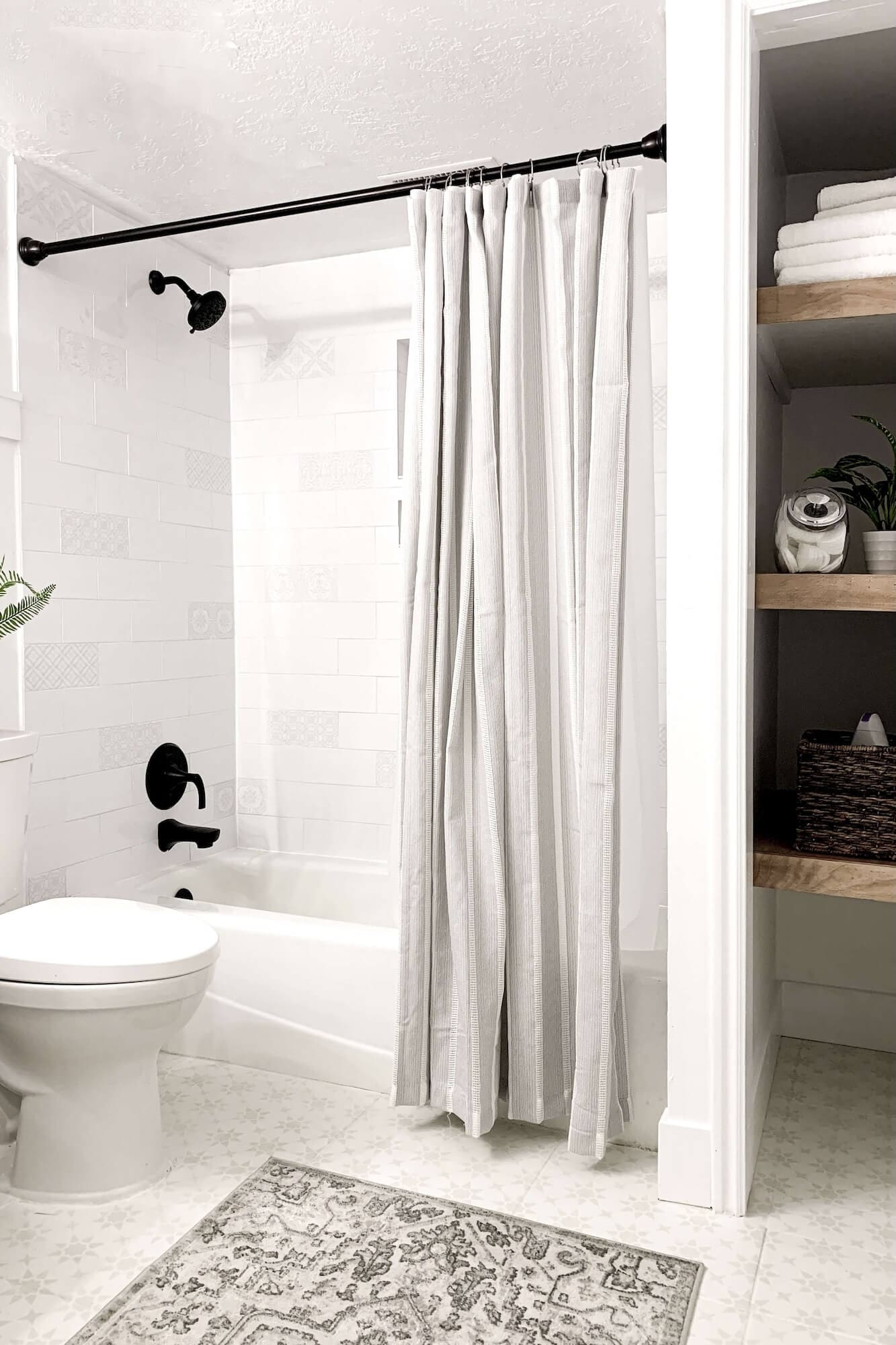 Overhead view of painted and stenciled bathroom floor tiles next to a dark green vanity and white board and batten wall.