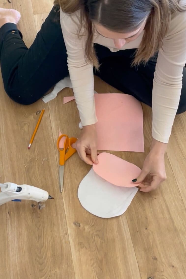 Positioning pink felt on a white fabric base to create the muzzle for a DIY cow costume mask.
