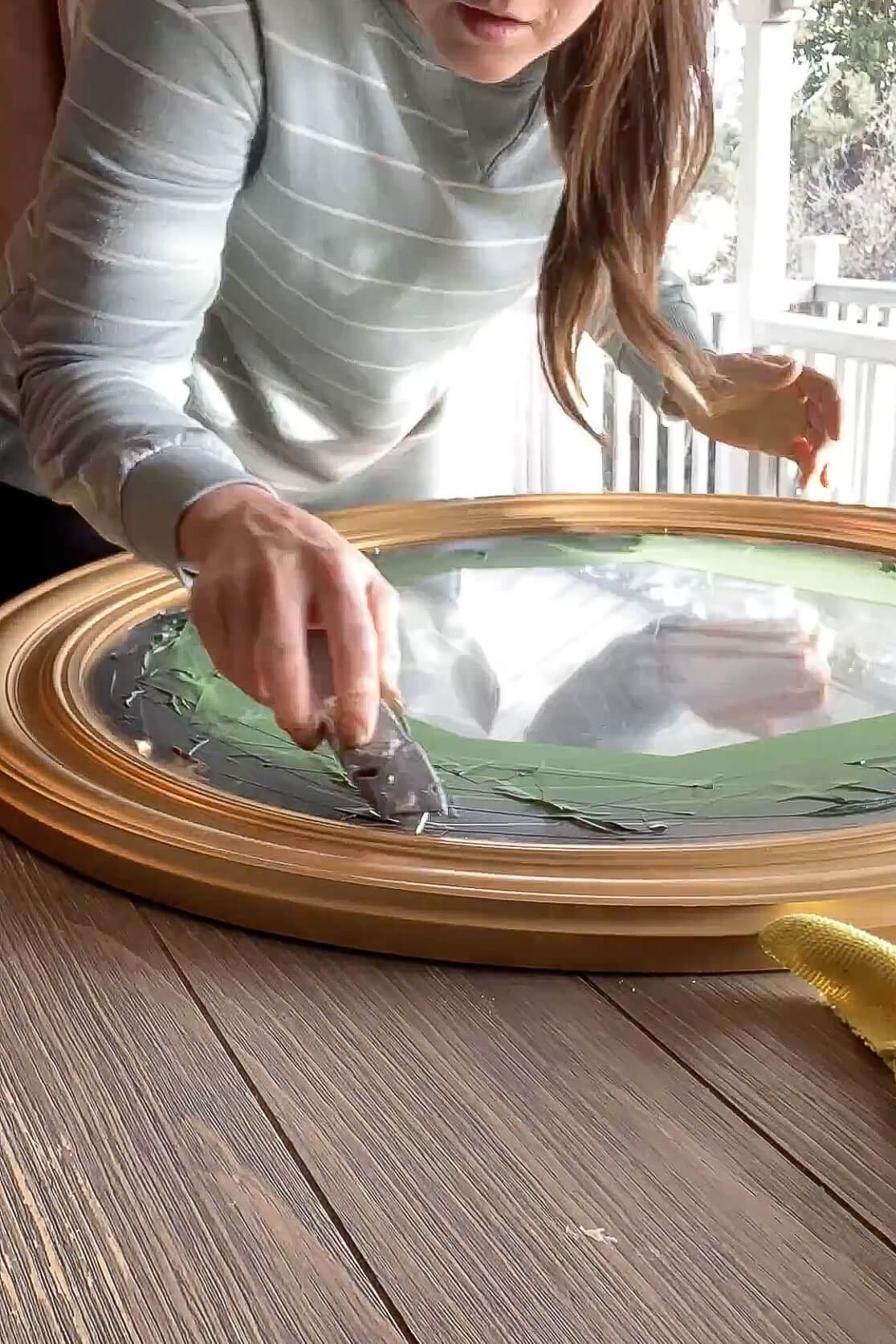 Hand rubbing Antique Gold Rub ’n Buff onto a mirror frame to create a warm gold finish.