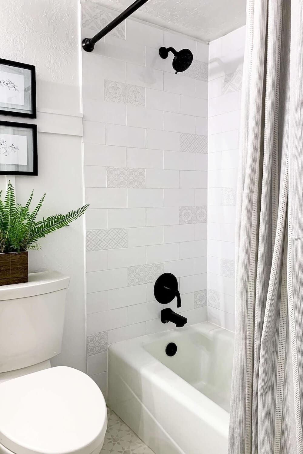 Finished white subway tile shower with double niche featuring patterned backs and matte black fixtures.
