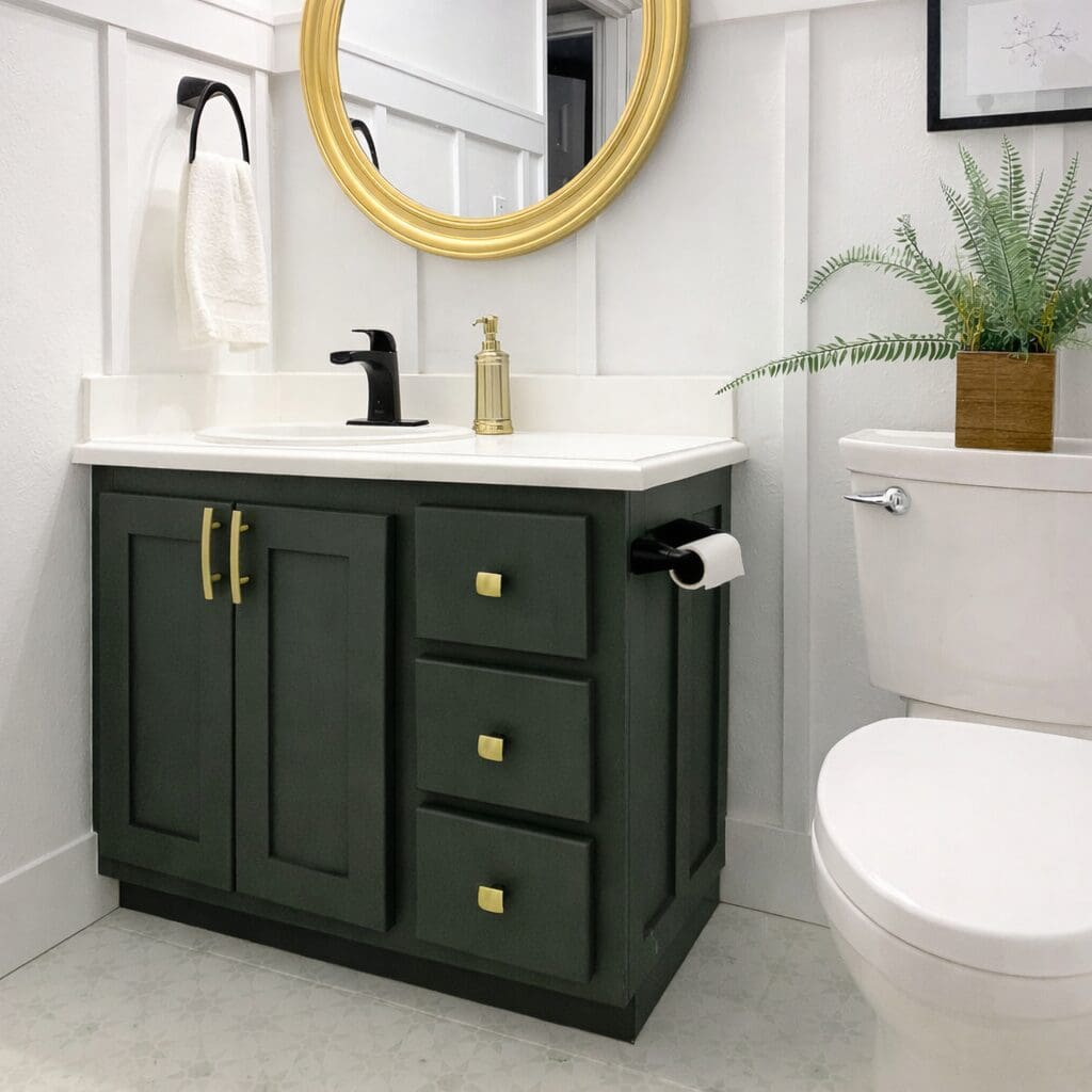 Painted bathroom vanity with new doors, black faucet, and gold hardware after budget makeover.