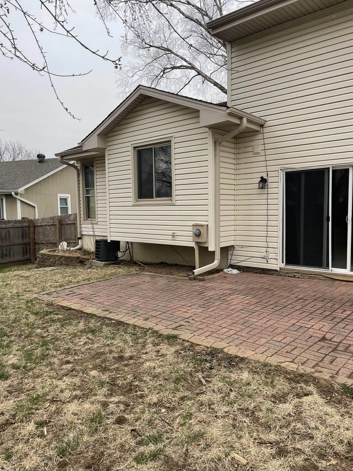 Backyard patio before DIY home renovation with old red bricks and no furniture