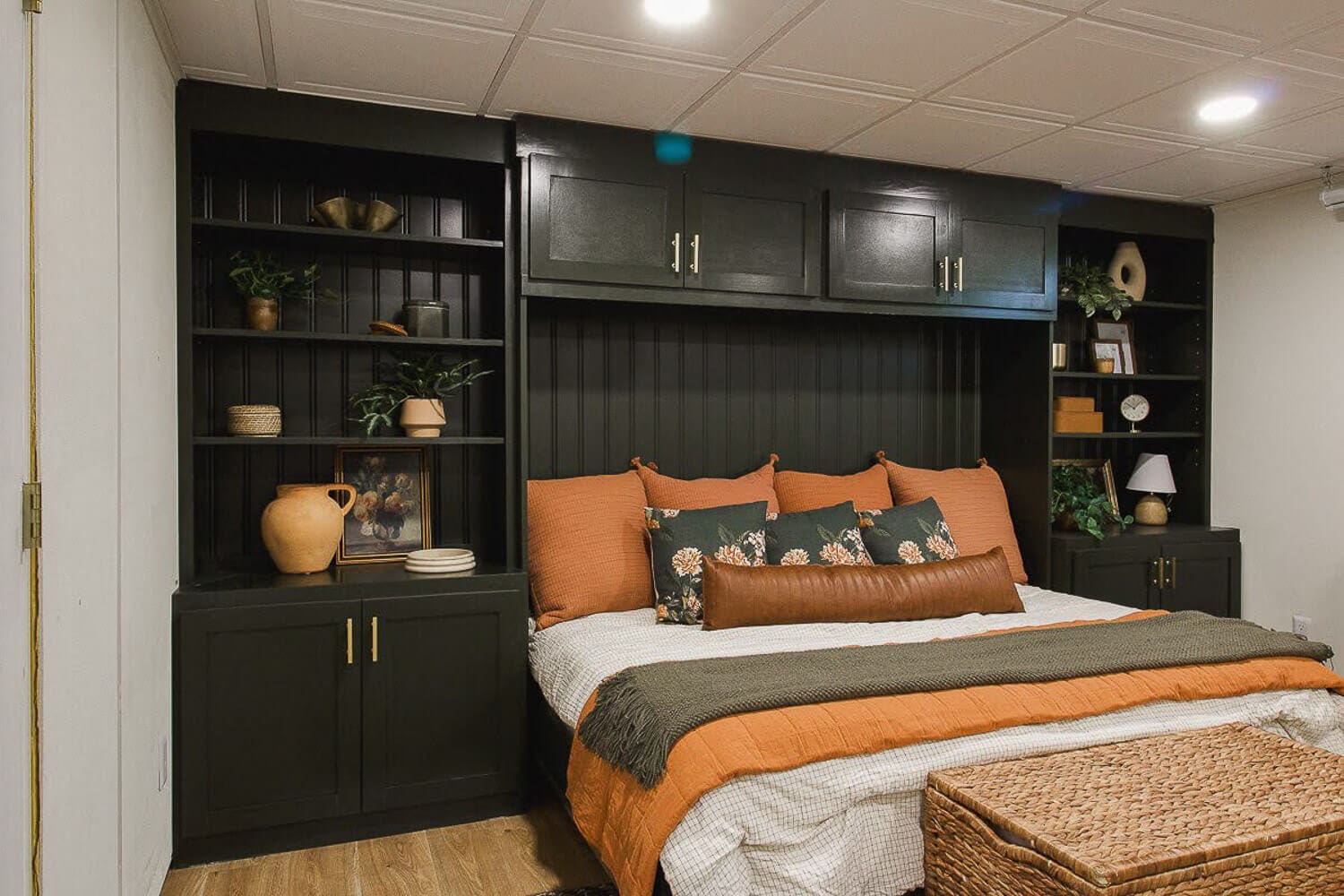 DIY basement bedroom remodel with custom dark green Murphy bed built-ins and styled bedding.