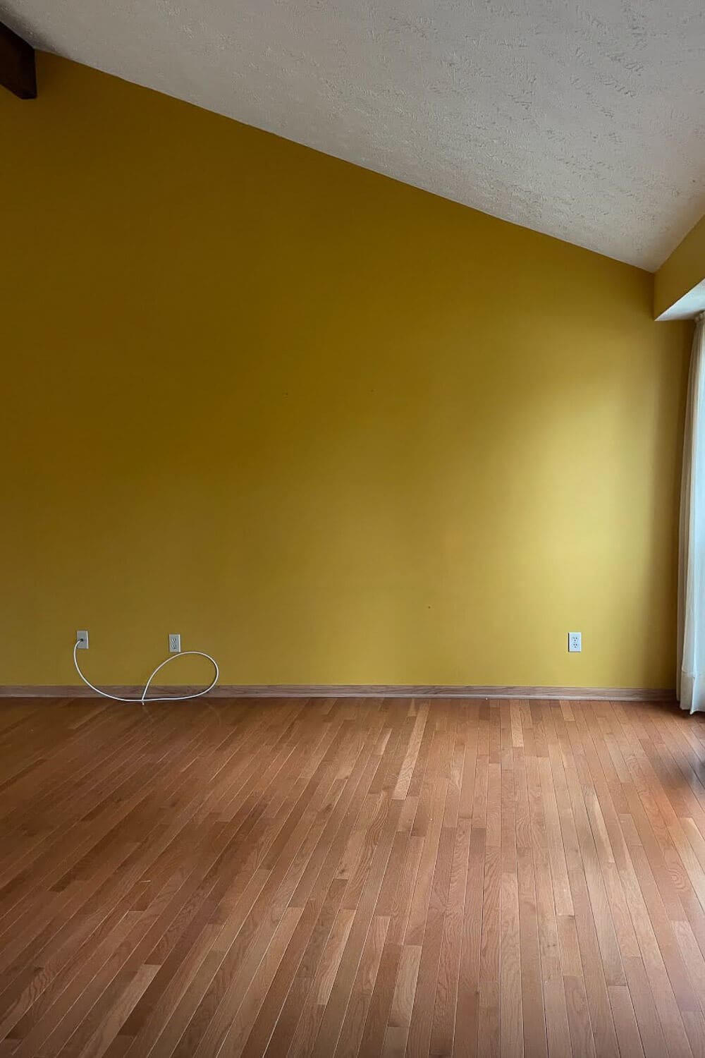 dining room before renovation with mustard walls and empty wood floor