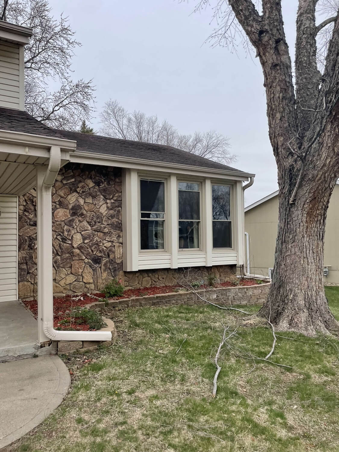 Split-level home before DIY home renovation with outdated siding and stone accent