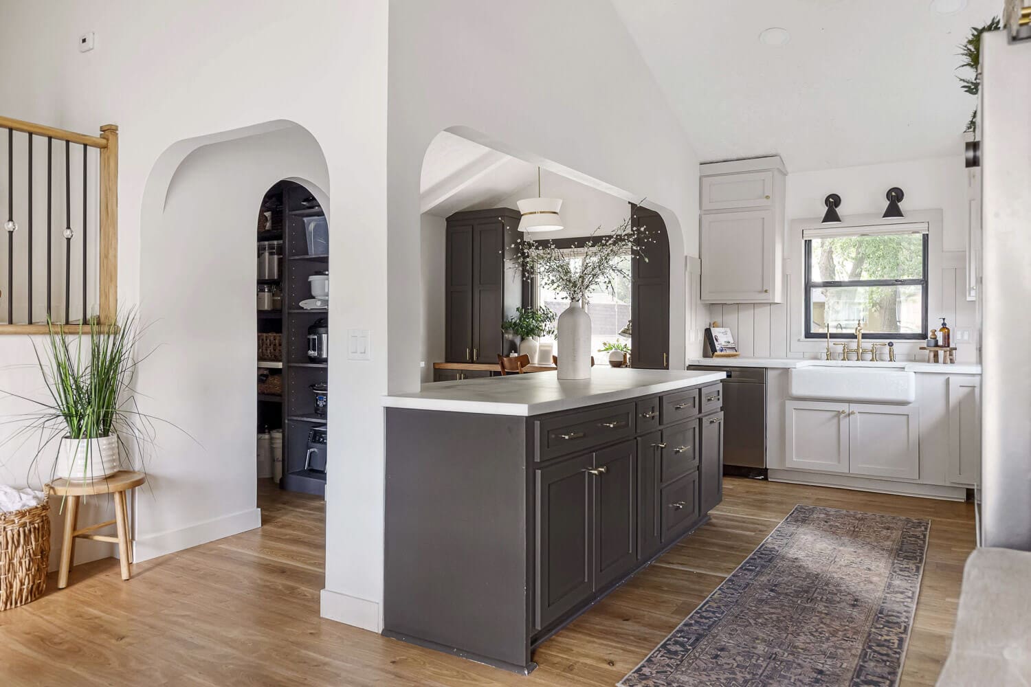 open-concept kitchen with arched openings, long island with dark cabinets, and farmhouse sink