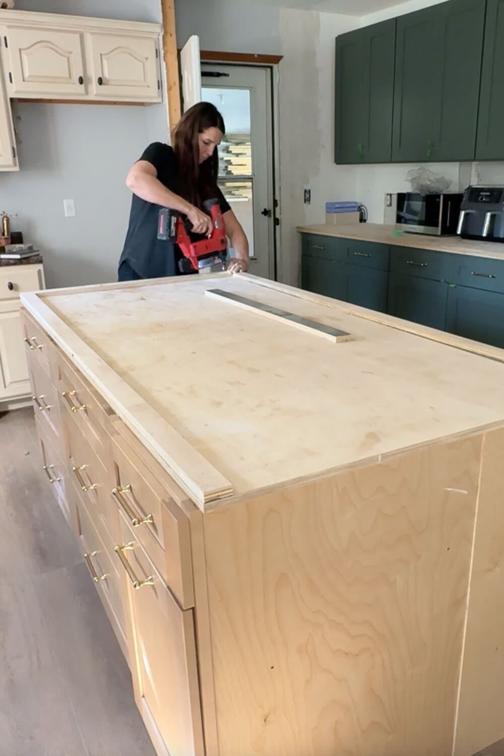 DIY island counter build showing plywood base as edge trim boards are attached with a brad nailer.