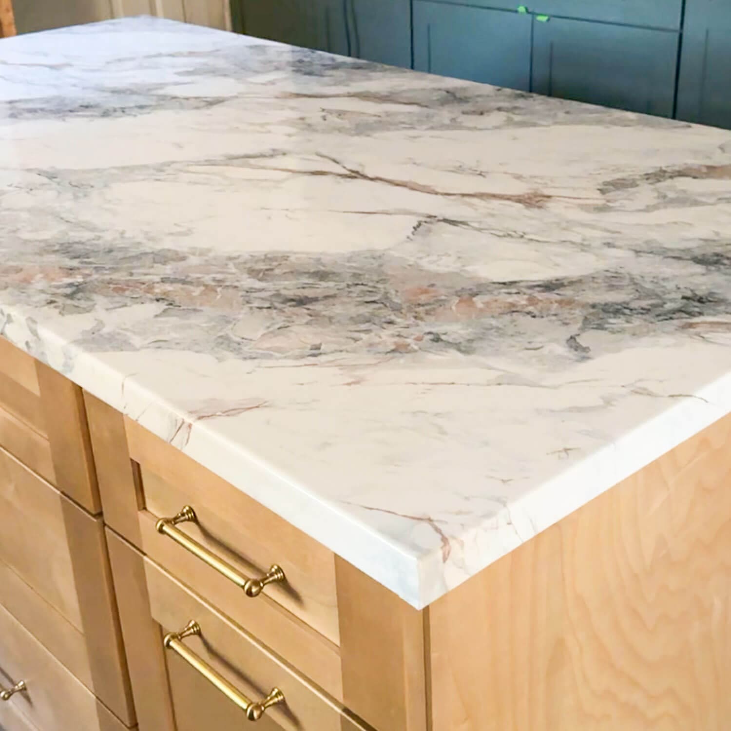 DIY faux marble kitchen island countertop made with contact paper, showing a realistic marble finish over plywood cabinets with brass hardware.
