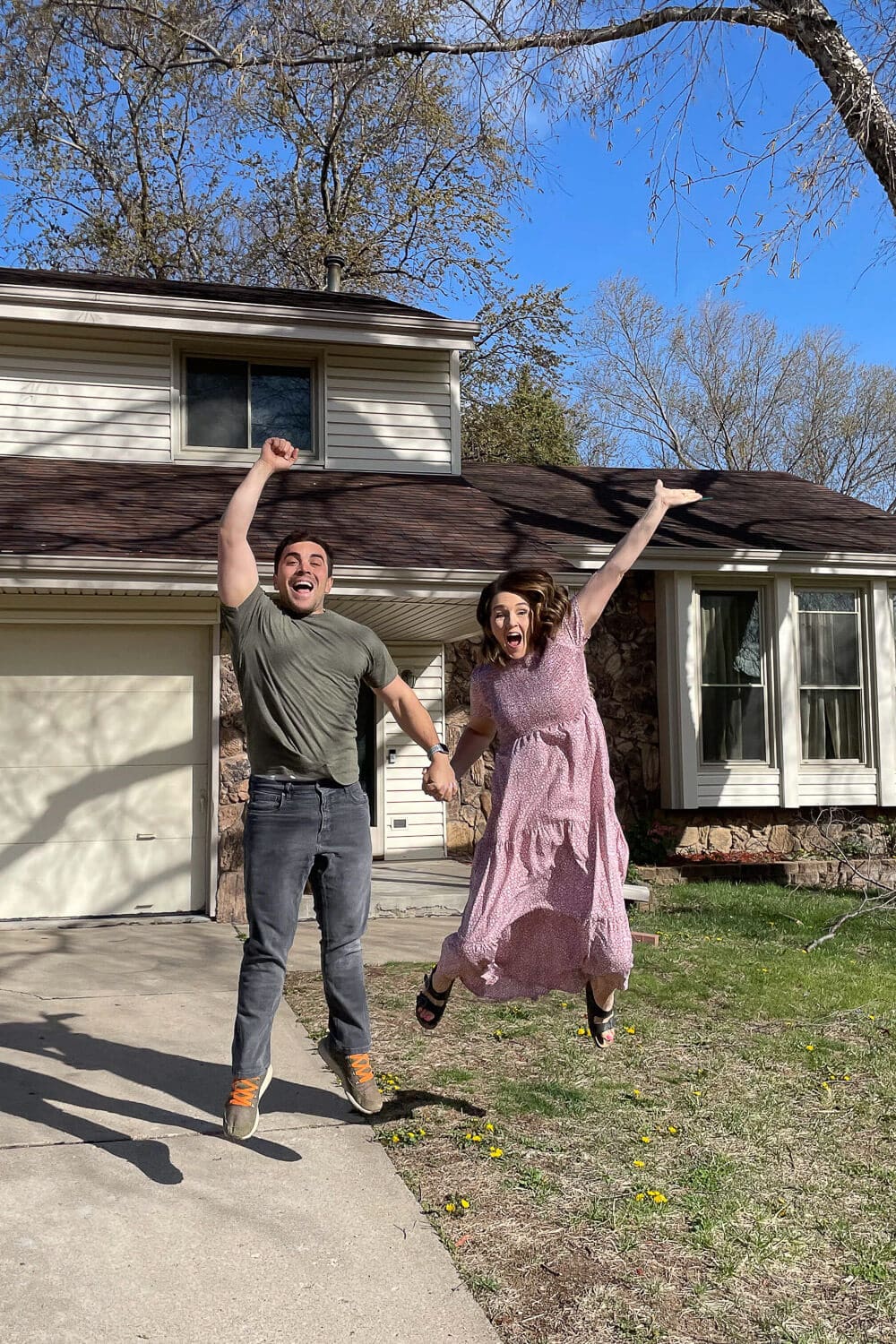 excited couple jumping in front of fixer-upper on move-in day