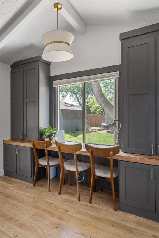 home office after remodel with dark built-ins, wood desktop, and three chairs