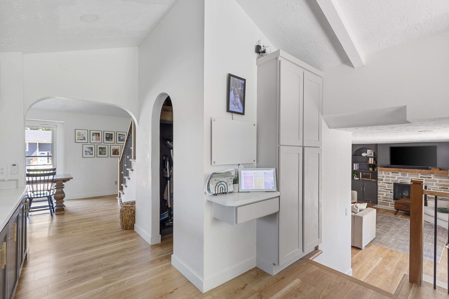 hall command center with slim built-in cabinet, small desk, and arched pantry nook