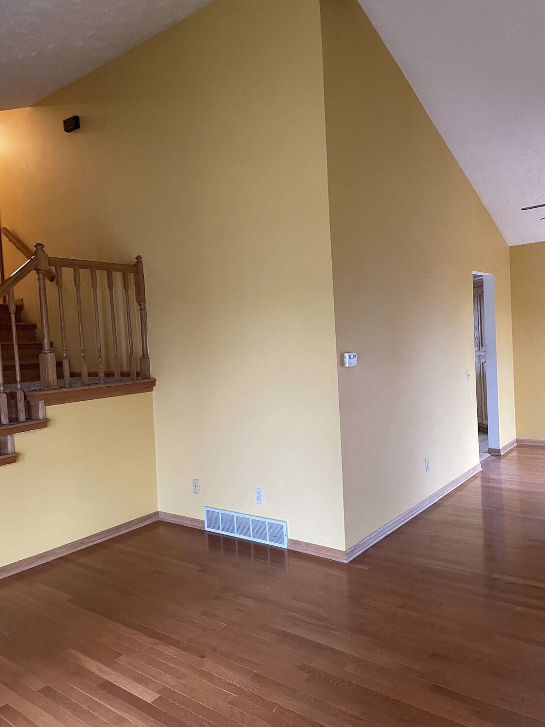 living room before renovation, yellow walls and dated railings by stairs