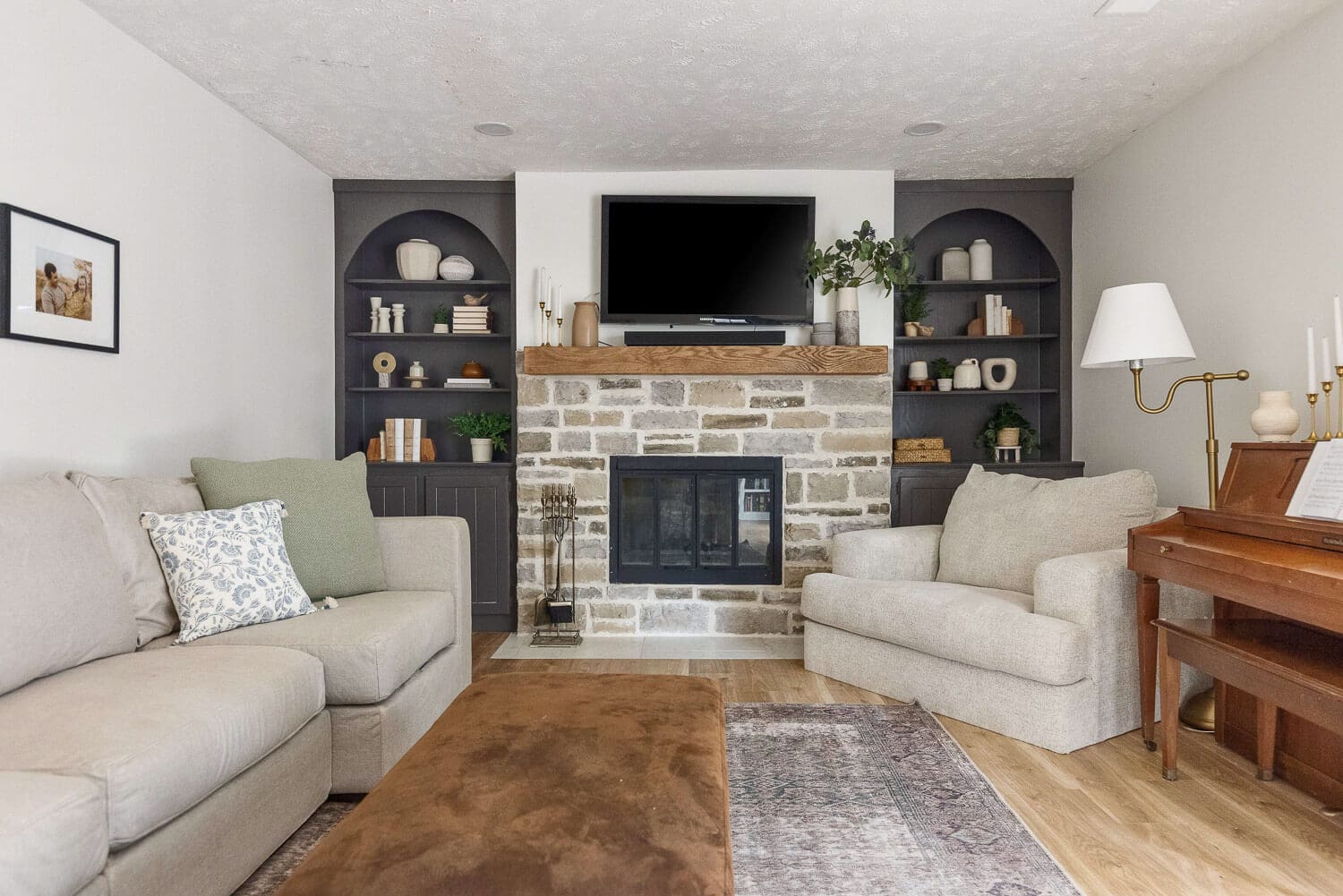 living room after remodel with stone fireplace, wood mantel, and arched built-ins