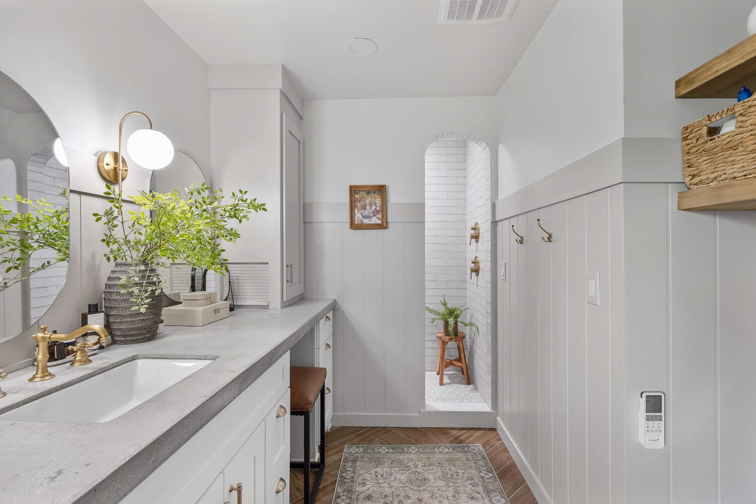 Primary bathroom after DIY remodel with gray shiplap, arched shower entry, and brass fixtures.