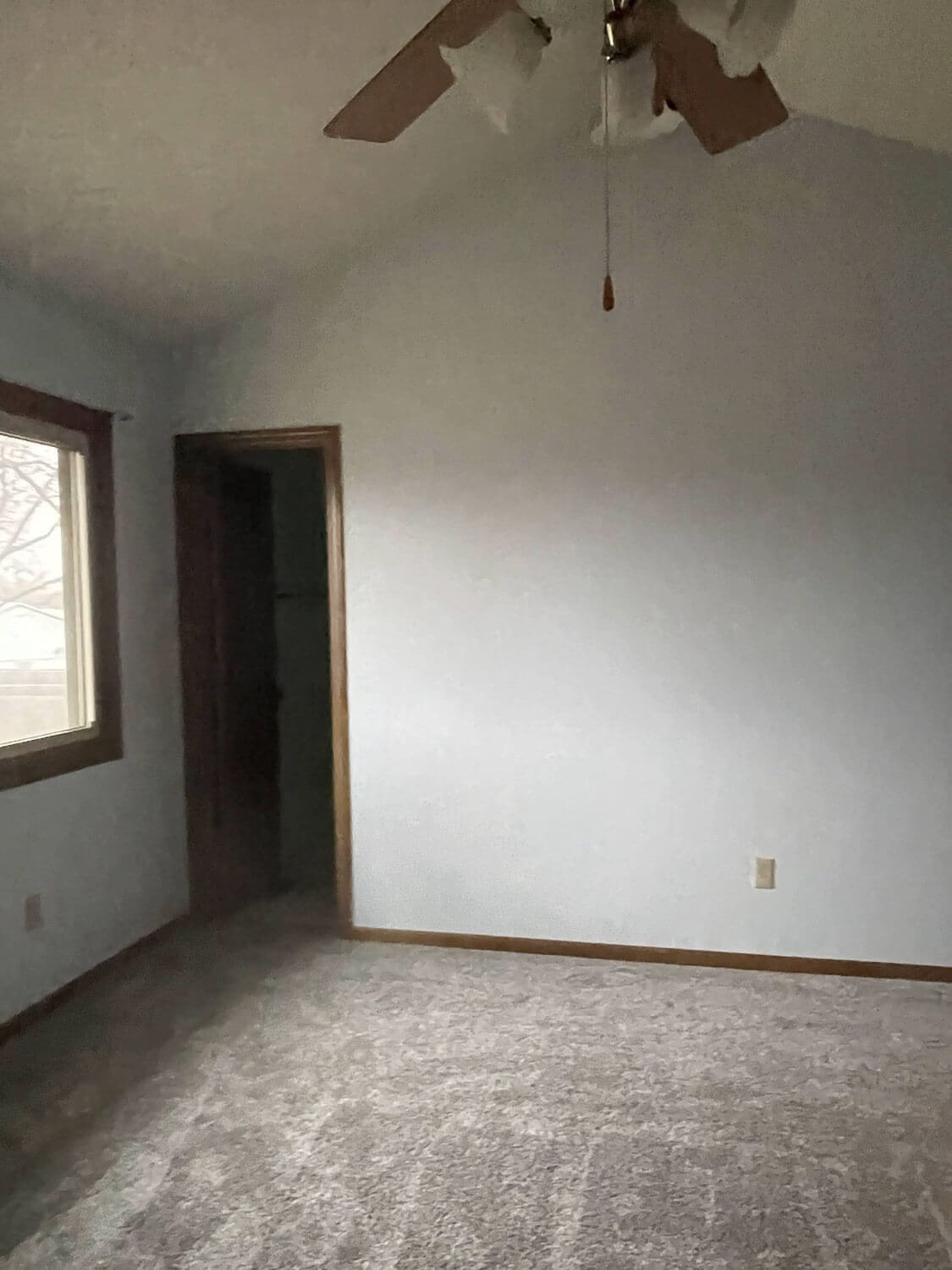 Outdated bedroom before remodel with popcorn ceiling and plain white walls.
