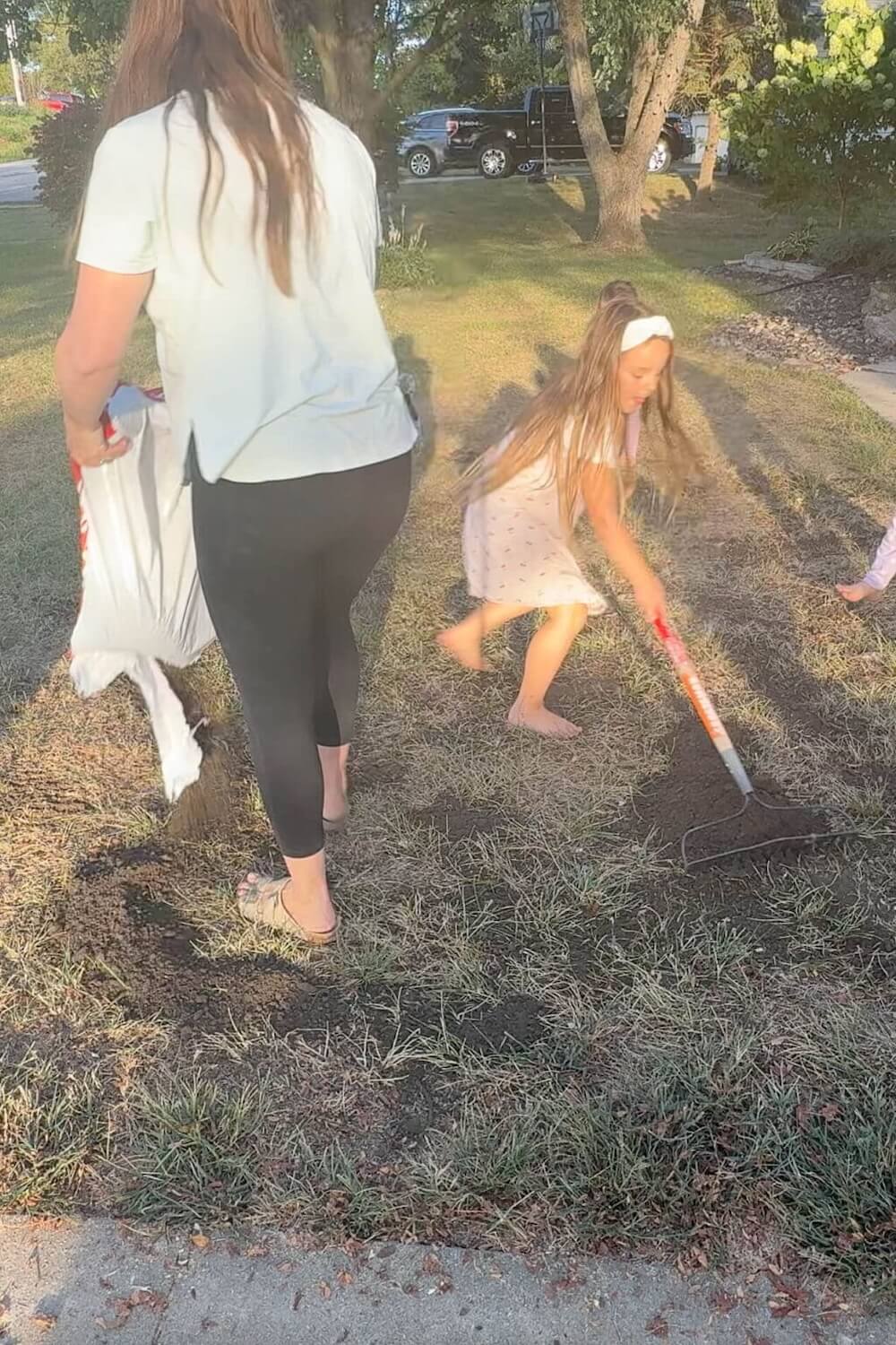 mother and child raking soil to cover seed