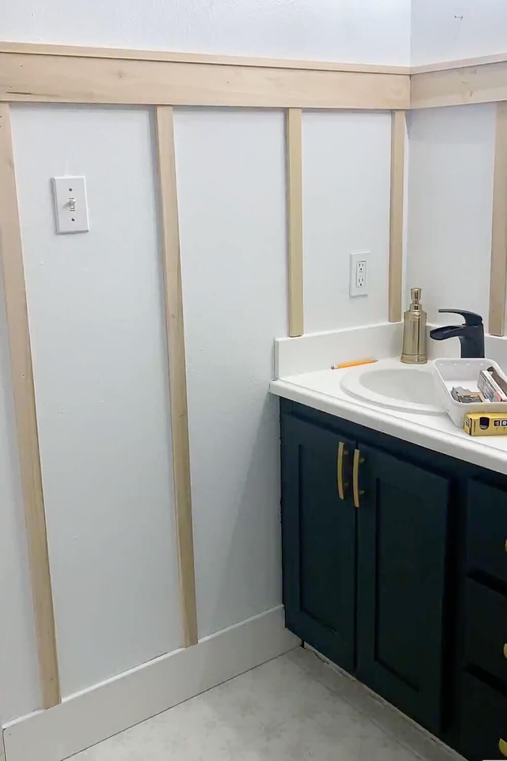 Board and batten wall installation progress with a 1x4 top rail and 1x2 vertical battens spaced along the vanity wall.