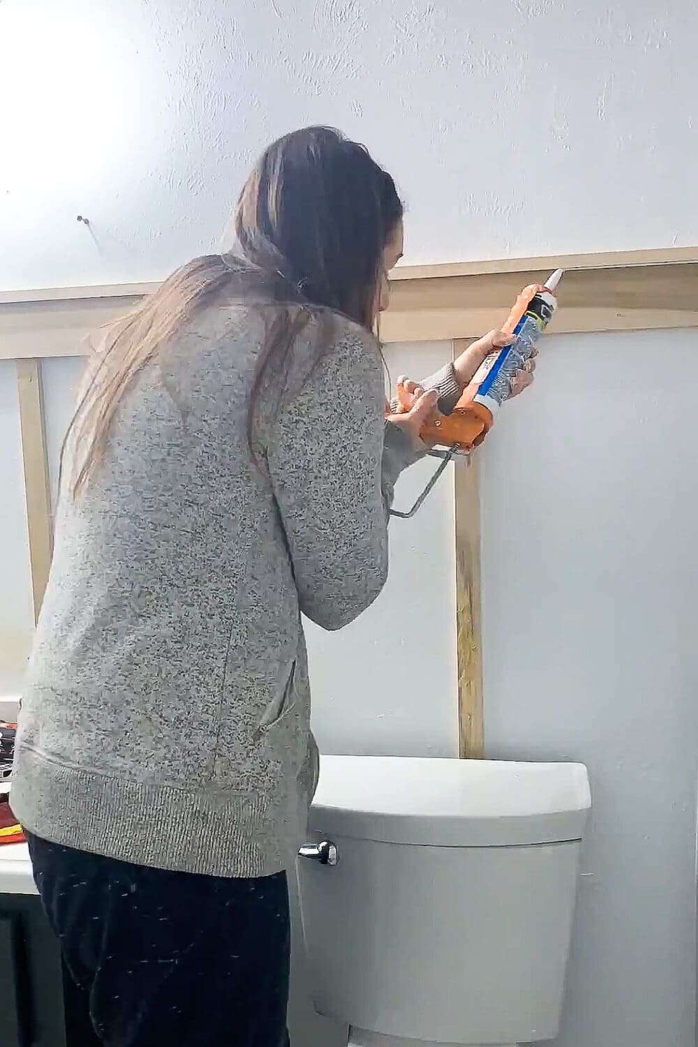 Caulking seams on a DIY board and batten bathroom wall to prep for primer and paint.